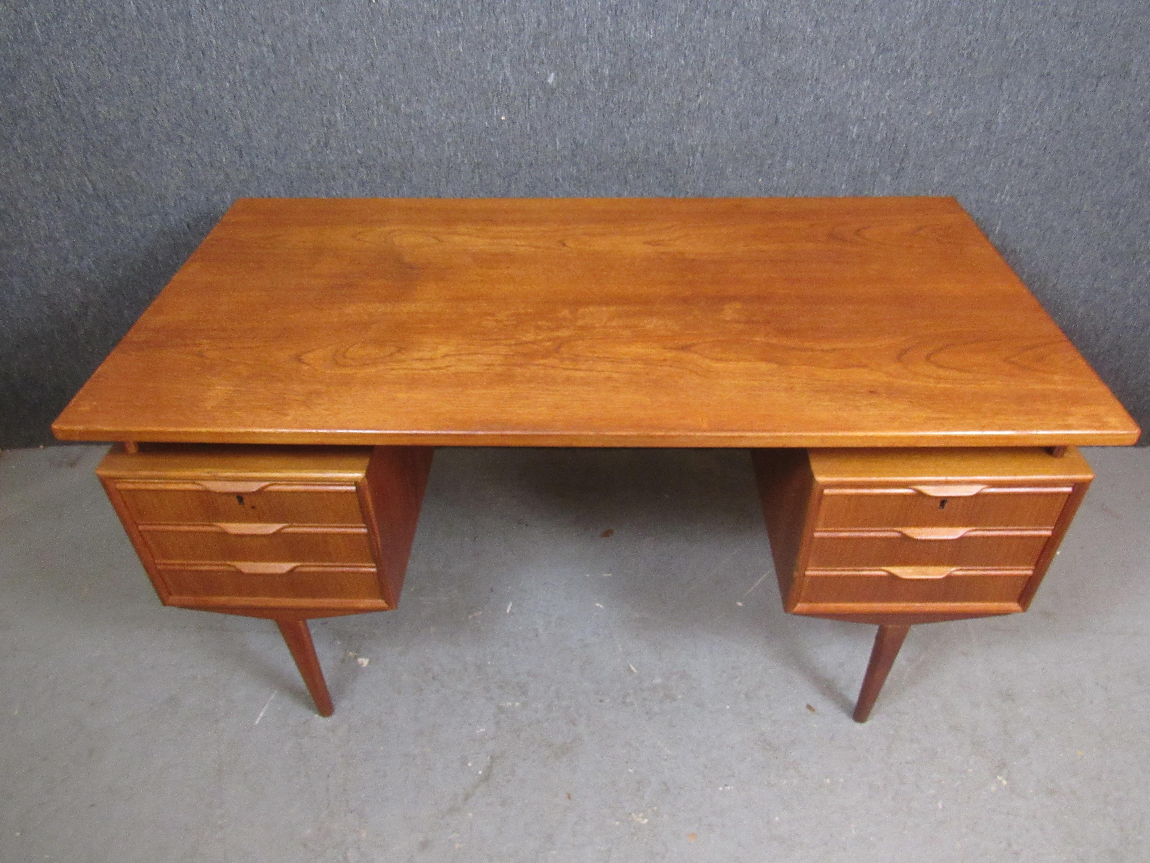 Whether in the home, office, or home office- this vintage Scandinavian teak desk is sure to impress! With a stunning floating top, sculptural pedestal legs, generous teak grain, and a fully-finished back featuring an ingenious built-in bookshelf