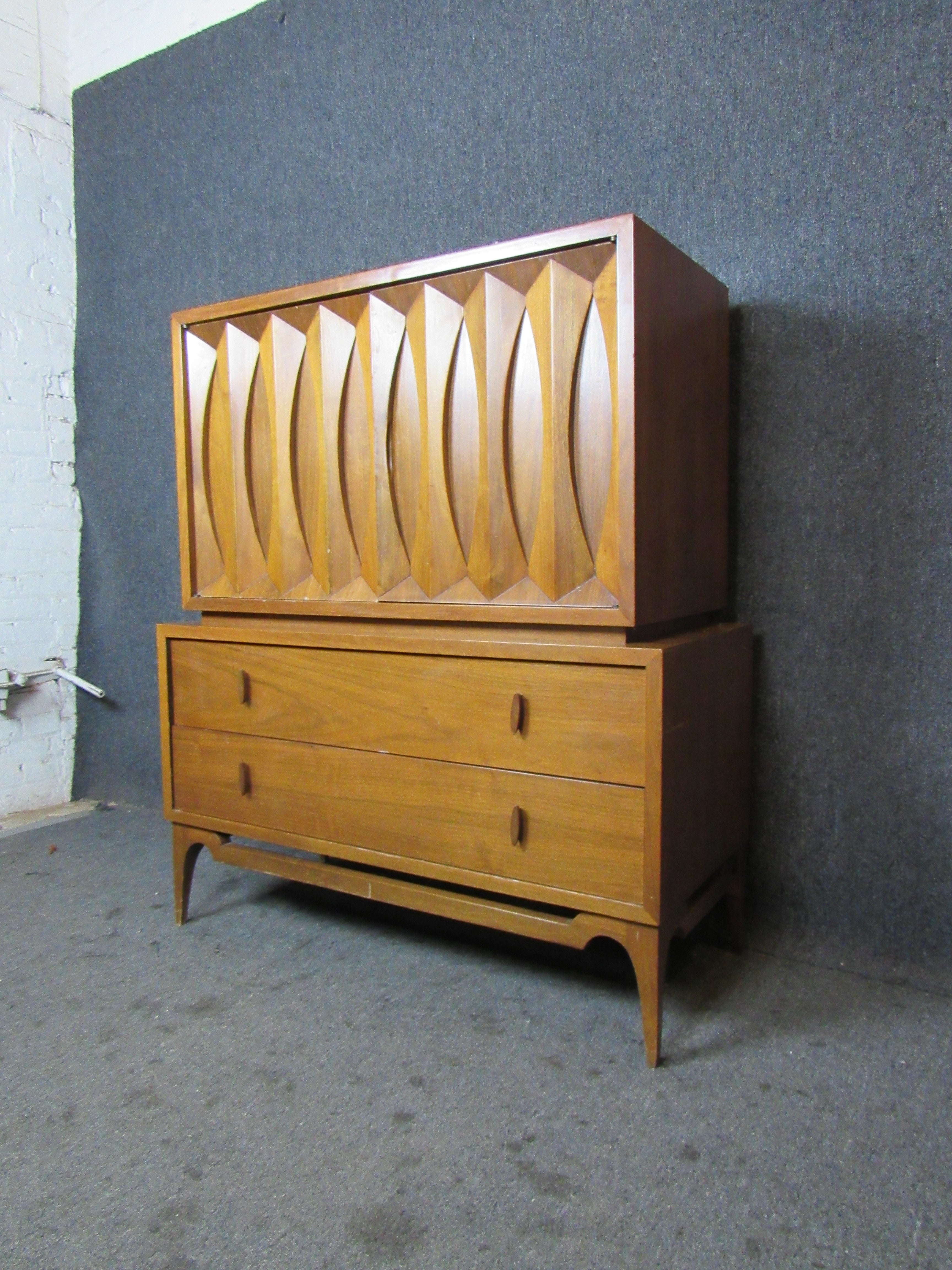 Endlessly interesting Vintage Mid-Century Modern walnut highboy dresser with fantastic sculpted details. A pair of double doors feature a panel of carved bowties reminiscent of the Classic Broyhill Brasilia and Kent Coffey Perspecta lines of the