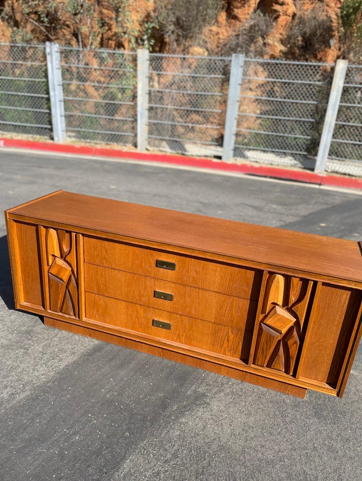Talk about a a statement piece!

This is a beautiful mid century modern tiki brutalist credenza. This dresser has a  stunning  carved design on the cabinet doors. Such a versatile piece for your home, it could make a great tv stand, bedroom dresser,