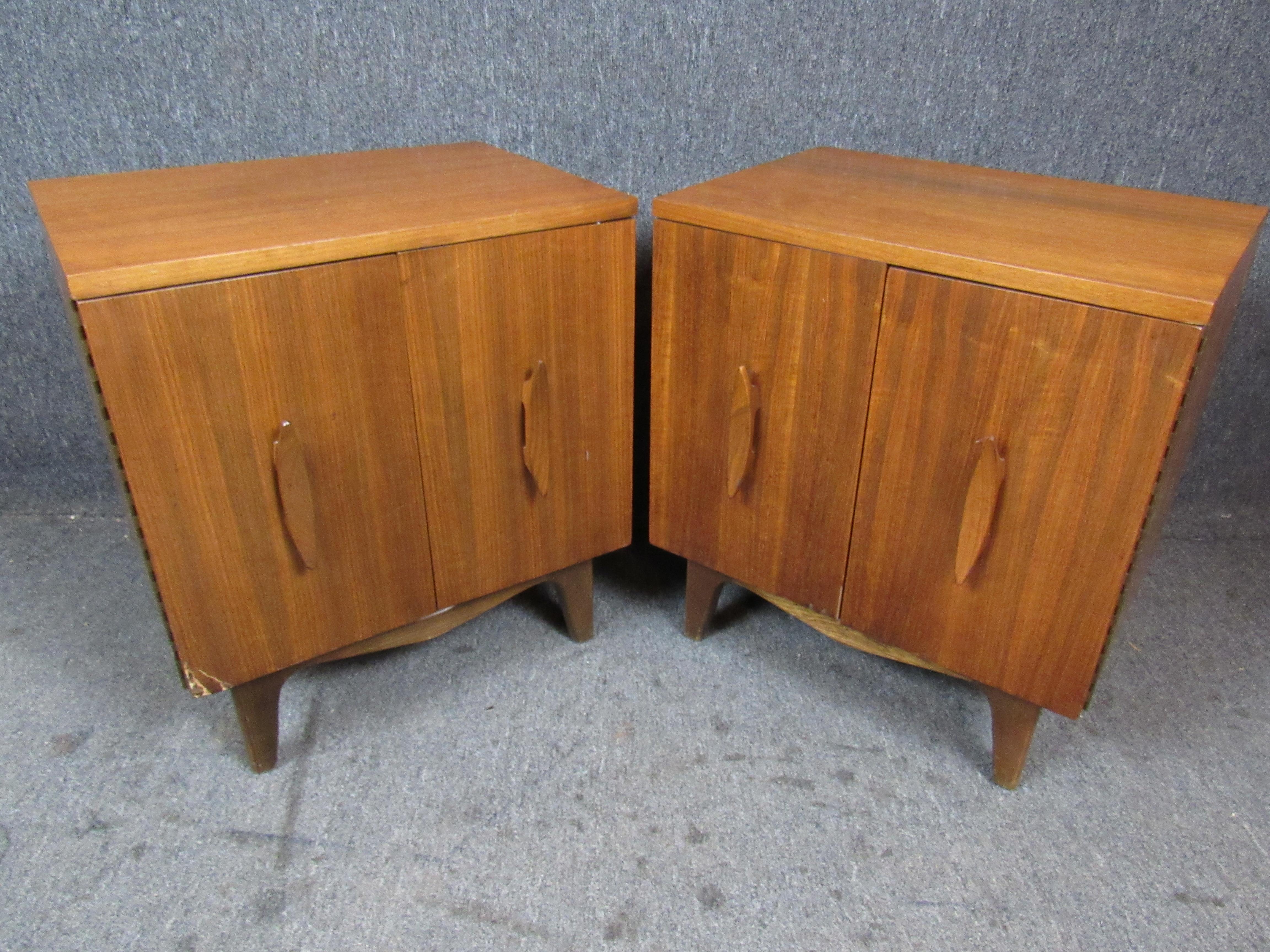 Wonderful pair of Mid-Century Modern featuring the authentic vintage patina that makes this style so desirable. Featuring sleekly sculpted canoe-like pulls and funky carved zig-zag legs, these cute little cabinets are sure to make a lasting