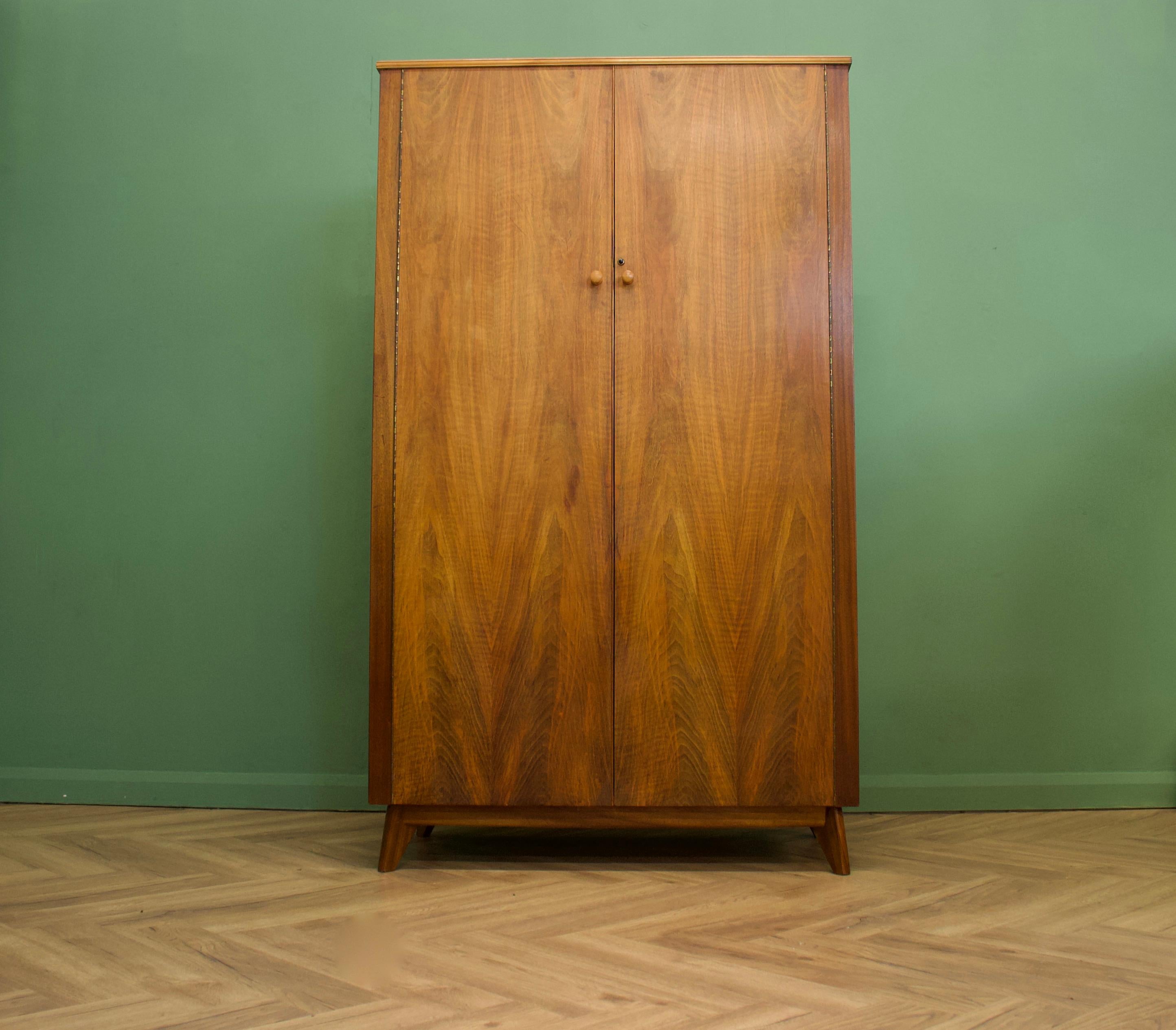 - Mid-Century Modern wardrobe.
- Manufactured Morris of Glasgow in the UK .
- Made from walnut and walnut veneers.
- Featuring a hanging rails and shelves.