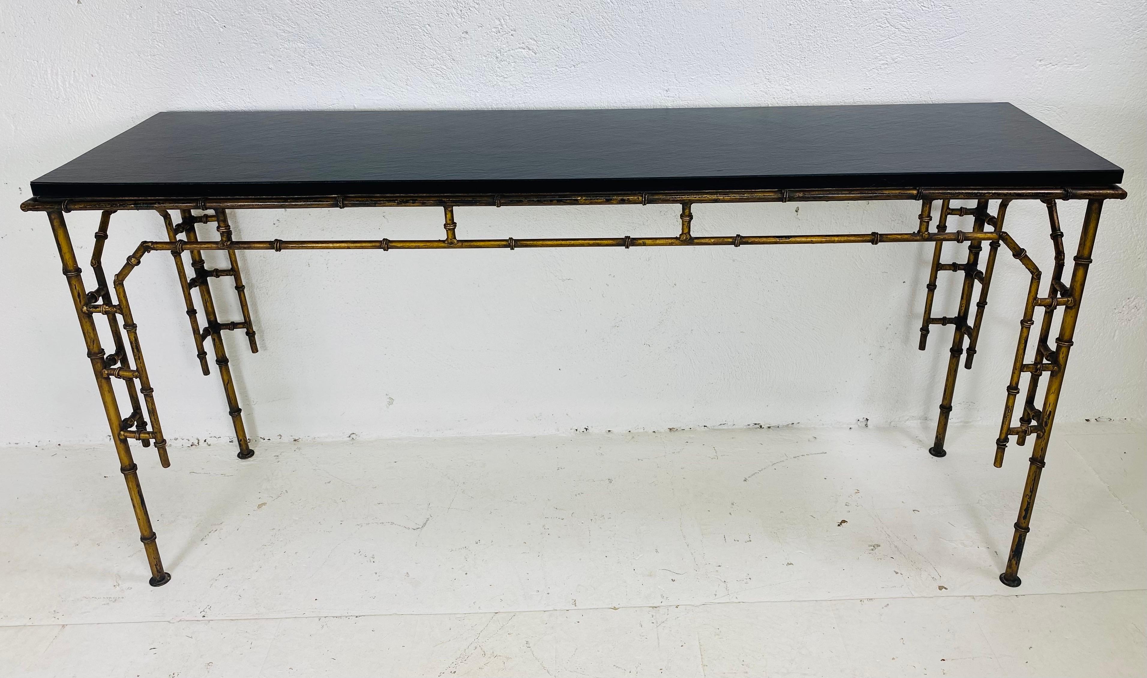 Se trata de una consola o mesa de sofá vintage de mediados de siglo de hierro forjado imitación bambú. Esta consola tiene un tablero de pizarra sintética y una base de hierro forjado con aspecto de bambú. Esta base de hierro forjado tiene un acabado