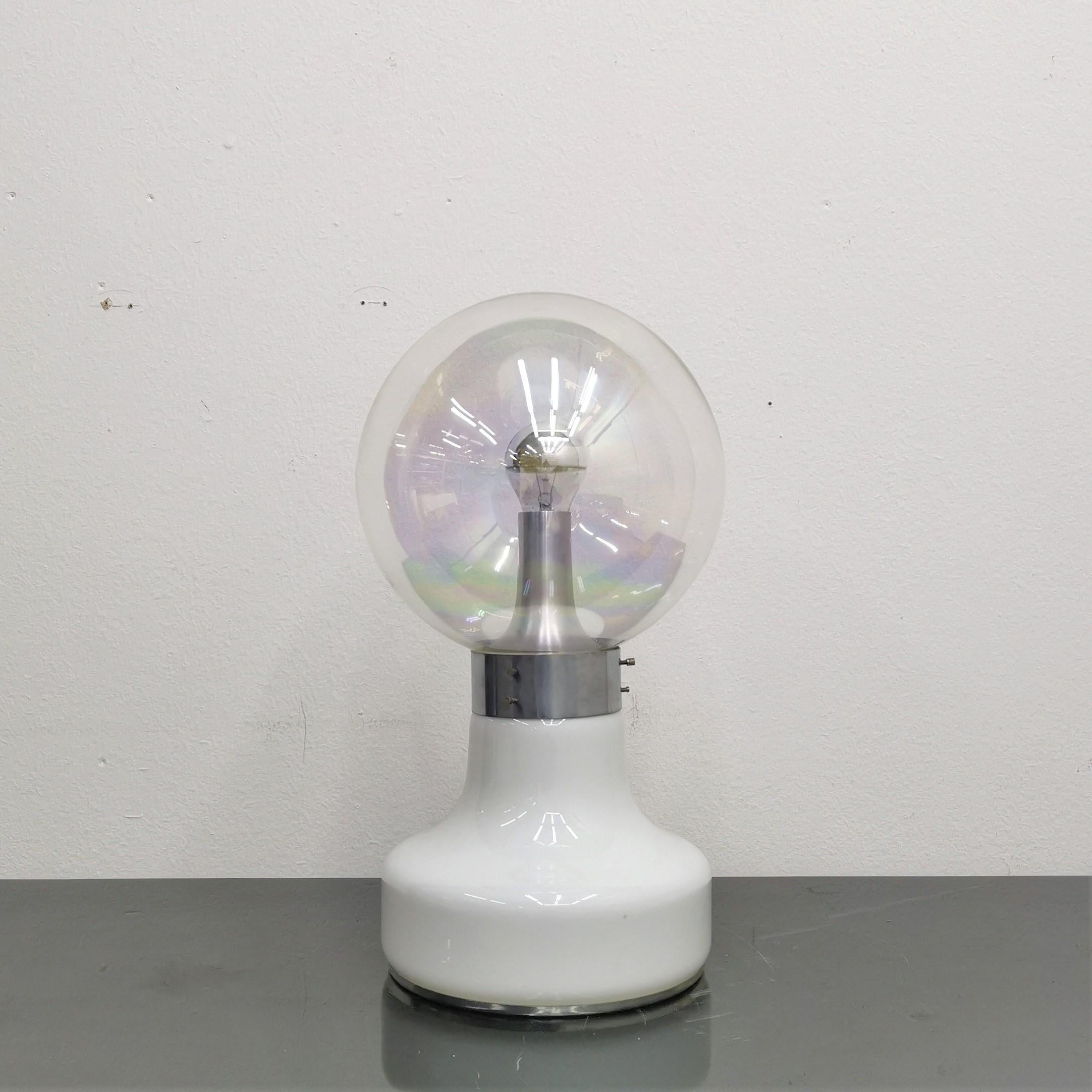 Gorgeous Pop Art table lamp with white glass base and upper globe in transparent iridescent glass. Both the top and bottom diffuse a suggestive light. In style of Vistosi, 70s Italy.
Wear consistent with age and use.