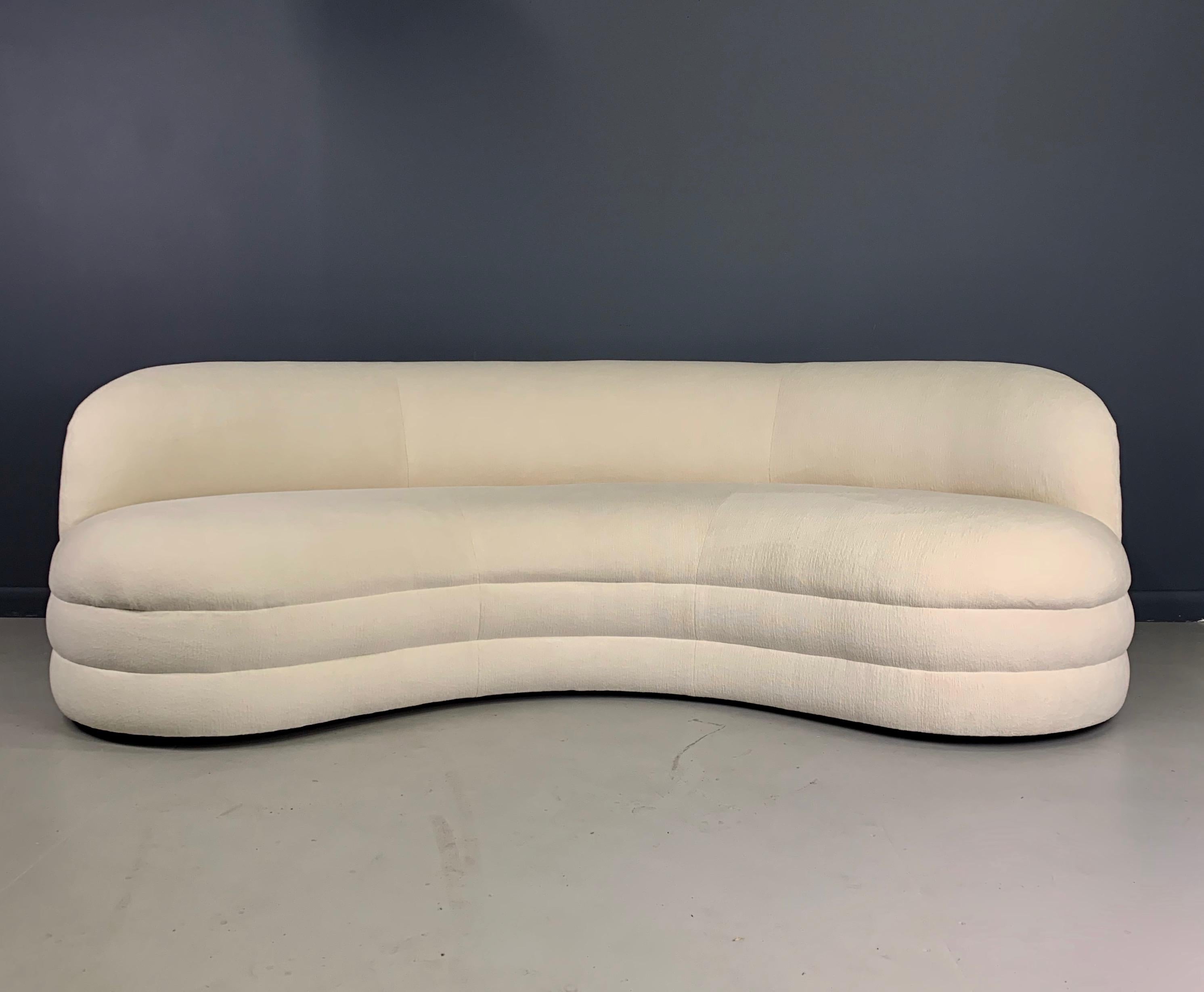 A unique kidney-shaped sofa, circa 1970s. The sofa features a nice sculptural modern design, with a curved arched back and a plinth base. The sofa has been redone from top to bottom with a beautiful textured white velvet. 

Measures: 84