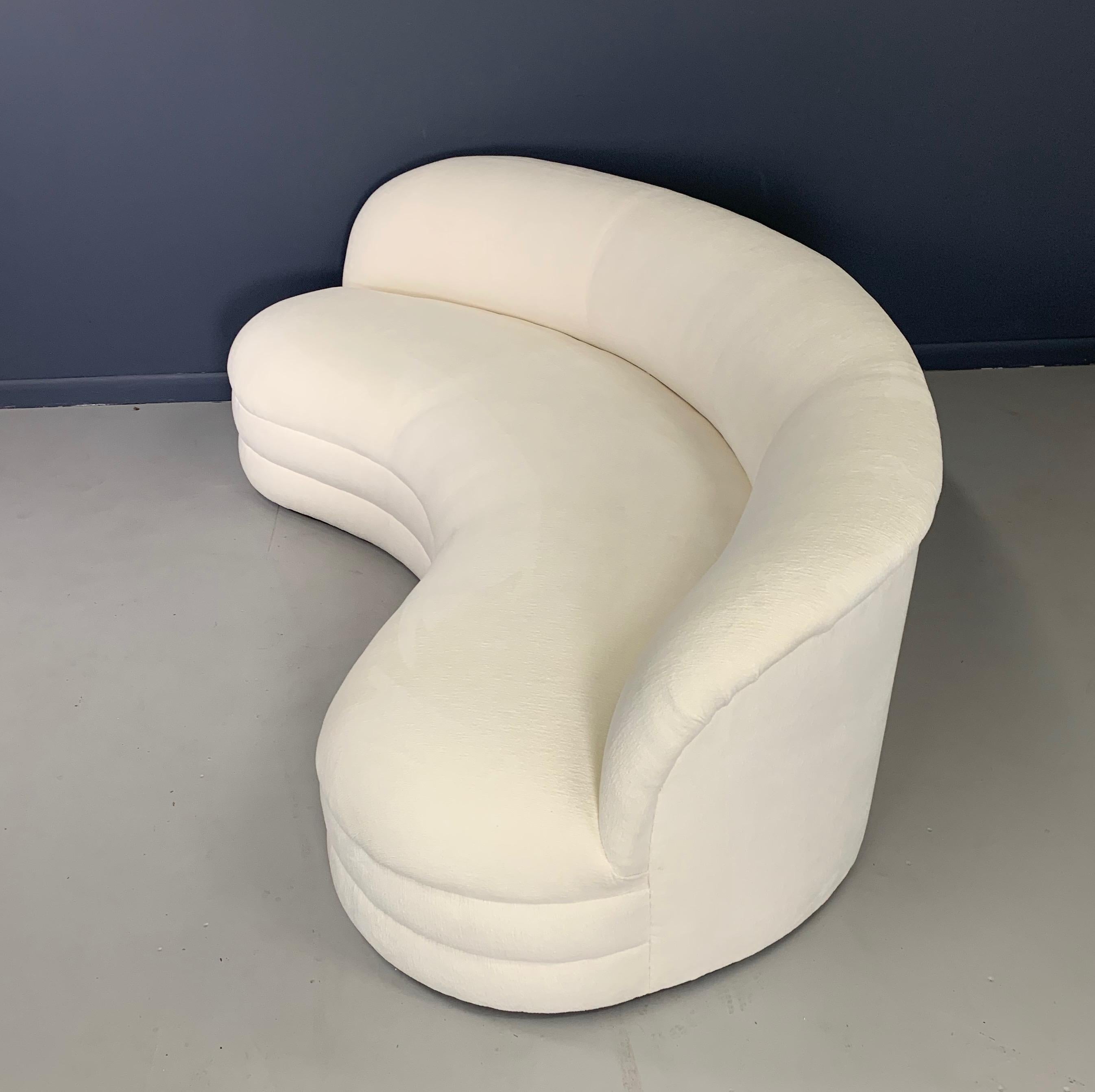 A unique kidney-shaped sofa, circa 1970s. The sofa features a nice sculptural modern design, with a curved arched back and a plinth base. The sofa has been redone from top to bottom with a beautiful textured white velvet.

Measures: 84