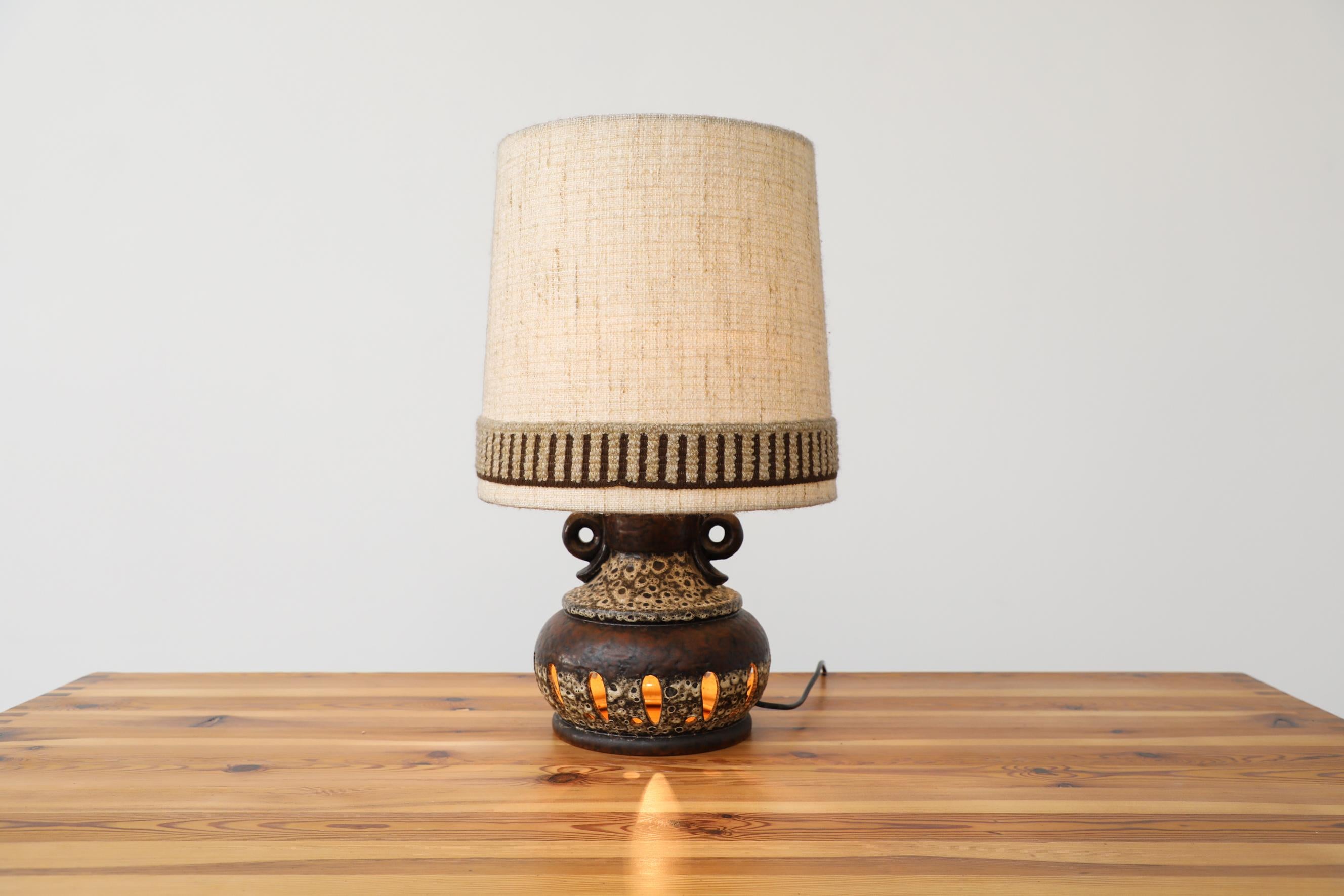 Midcentury W. German ceramic table lamp with cut-outs. This lamp has Dual lighting; one medium base above and a Euro candelabra light bulb below, illuminating the cut-outs. It has a 3-way switch allowing you to choose up, down lighting or both. It