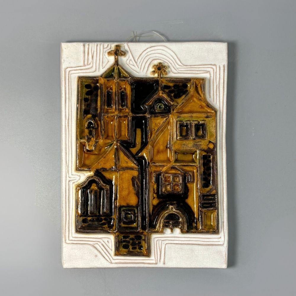 Mid-century Urbán Teréz wall ceramic from the period 1960-01970s. 
A geometric streetscape of Szentendre (Hungary) built in amber, mustard yellow and black on a white glazed base. 

Marked: Urban, Szentendre

About Teréz Urbán:

She was born in 1936