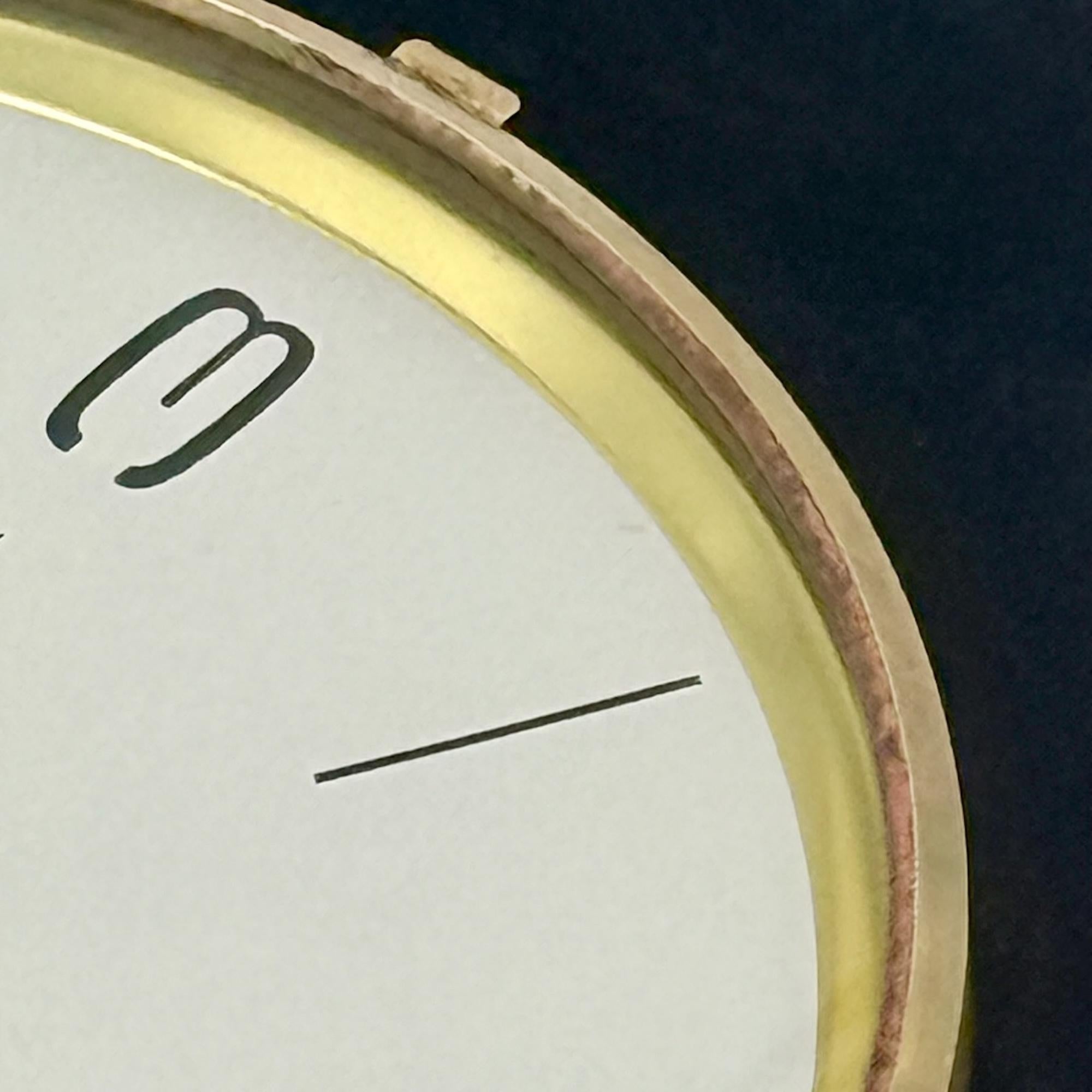 Elegant and rare vintage wall clock produced in France by the renowned brand ODO. Its refined oval structure is crafted from black Formica, a popular material of the 50s and 60s known for its durability and sleek appeal. The beige dial features bold