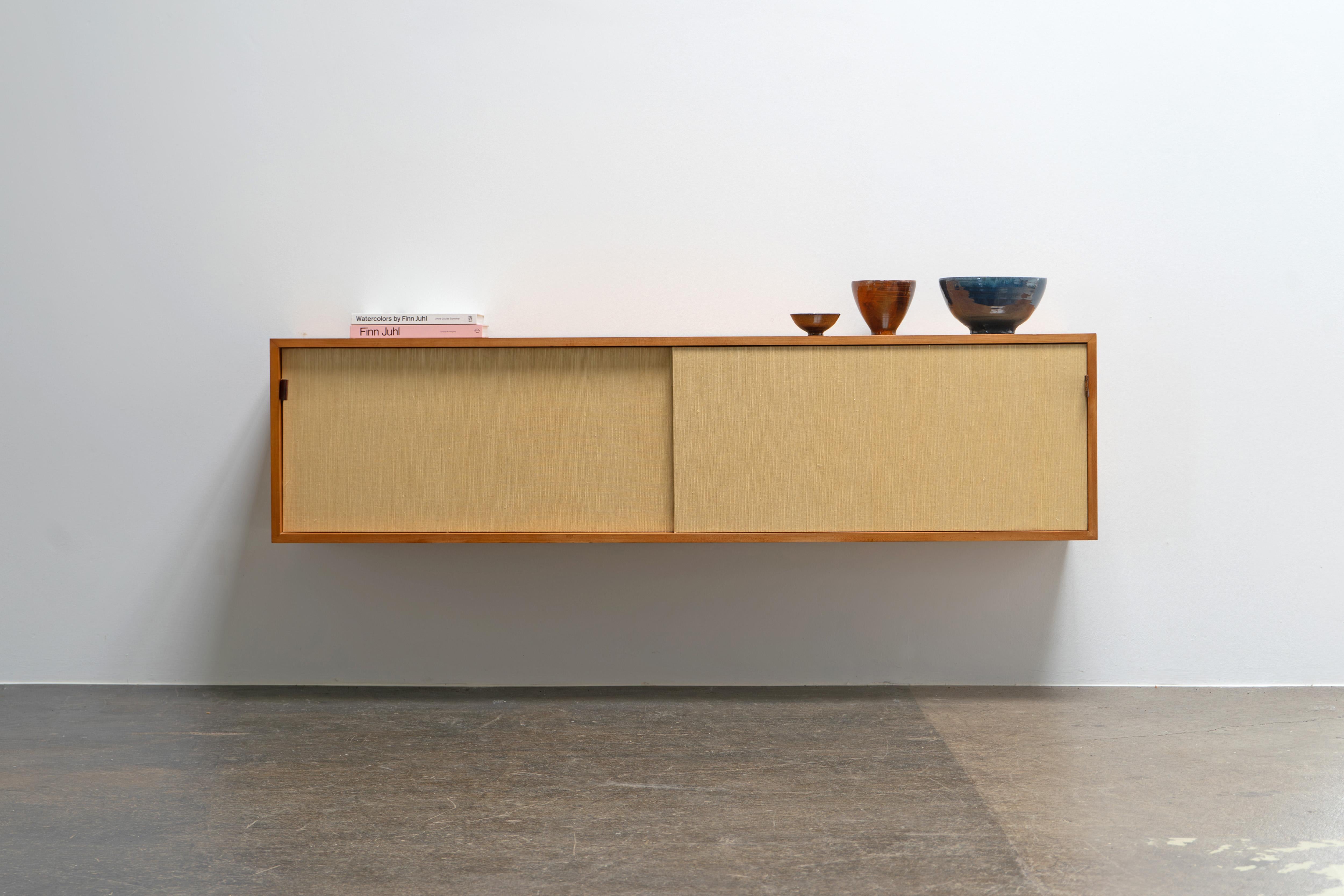 Extremely rare wall-hung sideboard (Mod°123) from 1958, designed by Florence Knoll for Knoll International - this version was produced in a small edition by Knoll in Stuttgart in 1958.

The sliding doors are covered with natural fiber, sewn leather