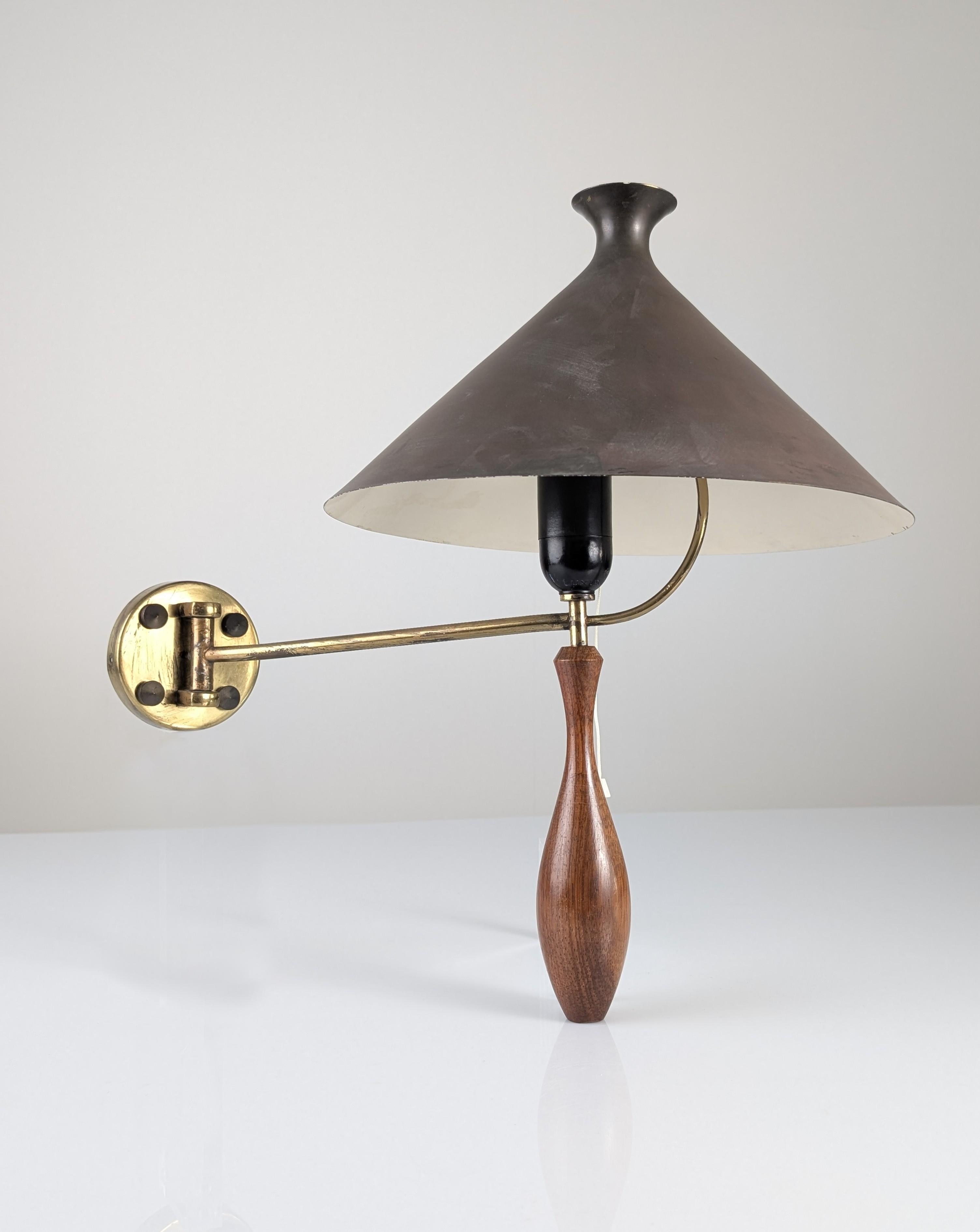 Wandleuchte aus der Mitte der 1950er Jahre mit einem eleganten Griff aus Massivholz, der fein in eine stilisierte Tropfenform gedreht ist. Das Design kombiniert einen Messingschwenkarm mit einem schwarzen Metallschirm in umgekehrter konischer Form,