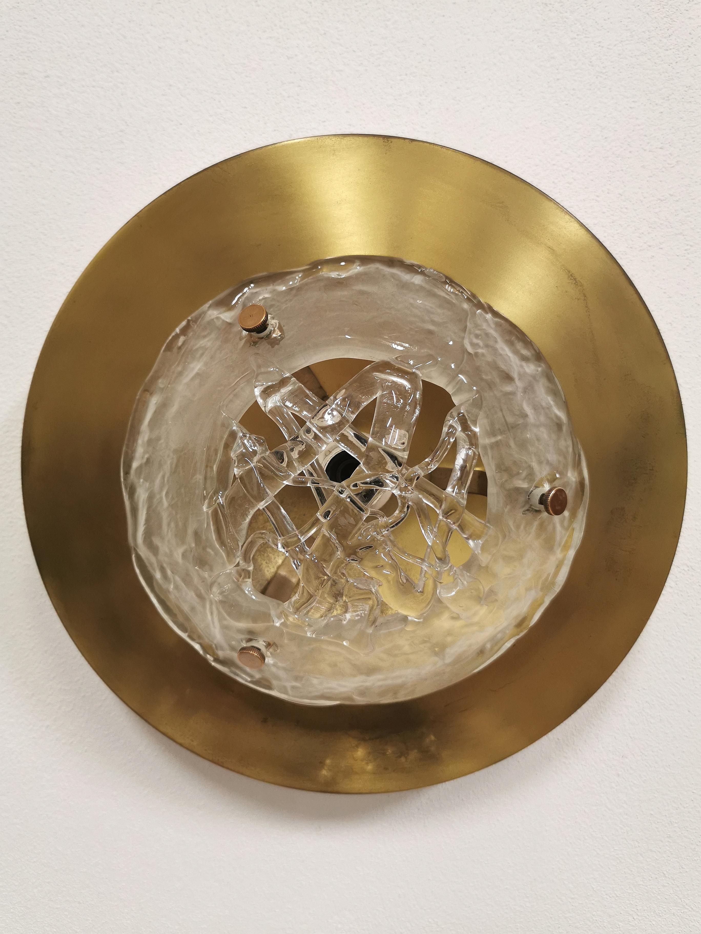 Wall lamp with an elegant design and appearance, Designed by Angelo Brotto and made by Esperia in Italy in the 1970s. The structure has a round brass frame where in the center of the lamp fixed with brass screws, there is an artistic Murano glass,