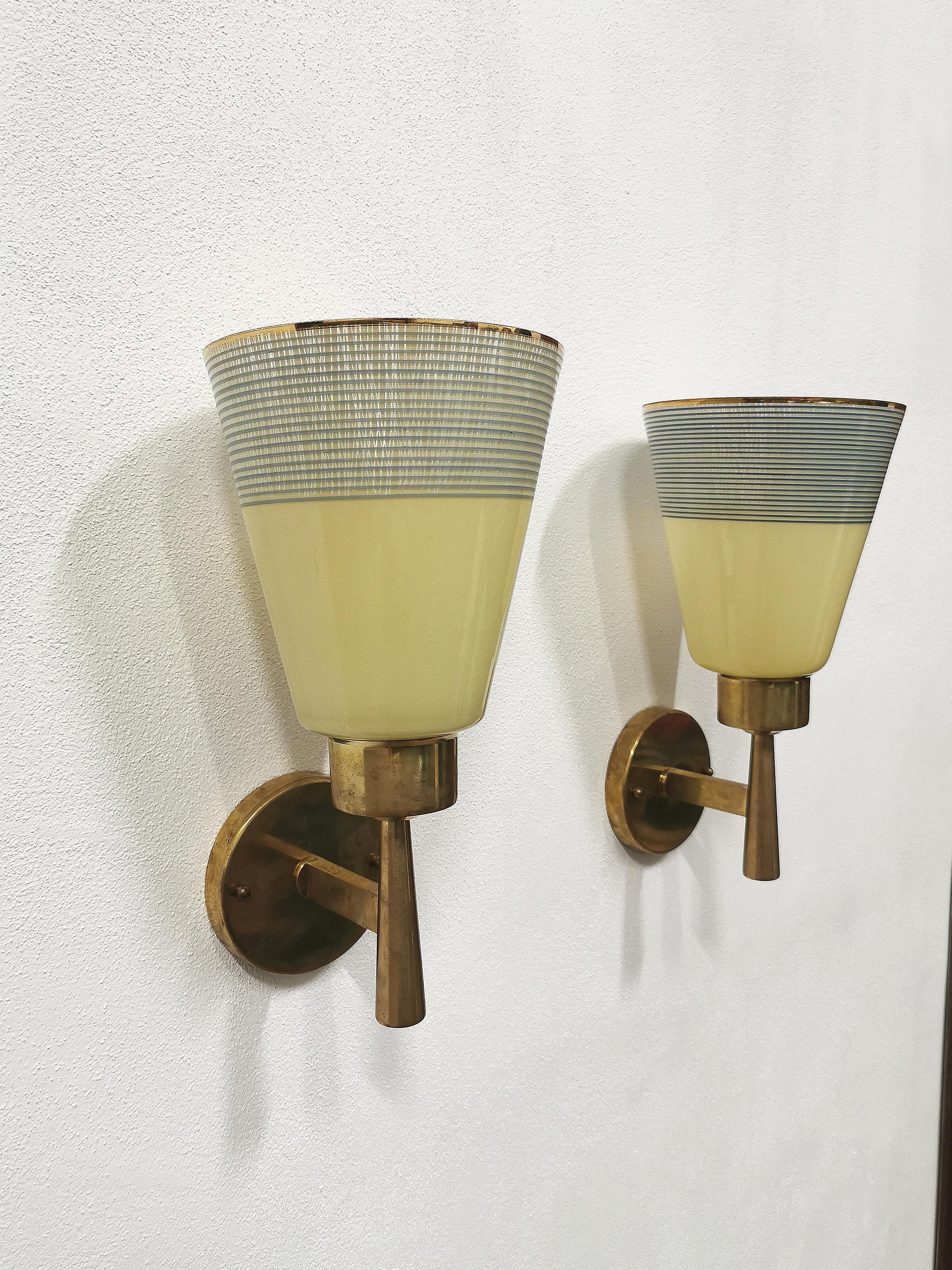 Pair of wall lights with diffuser in yellow crystal glass decorated with light blue stripes and gold trim on the upper part of the diffuser. Brass structure, Italian production of the 1950s.