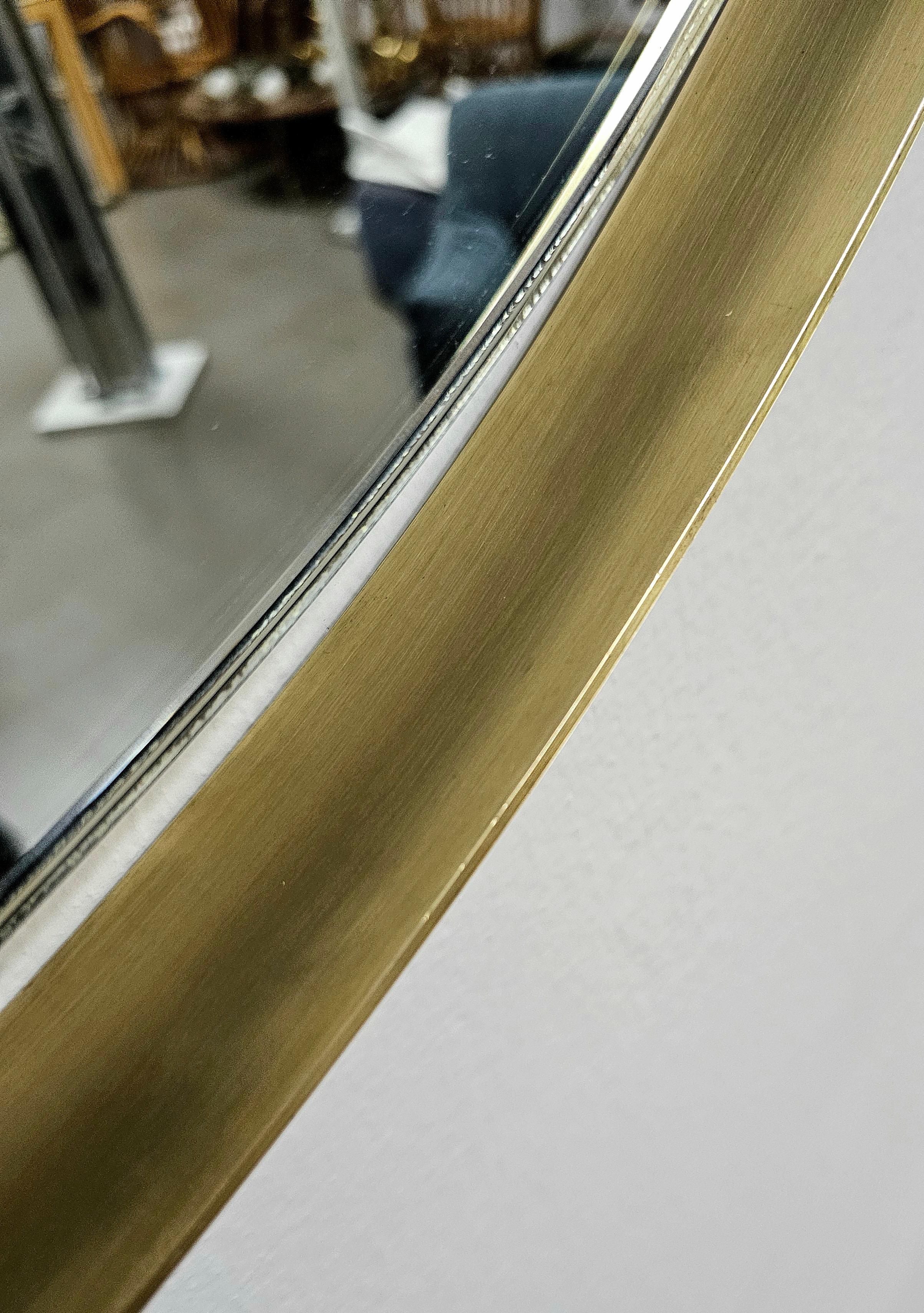 Large circular wall mirror with brass frame. Produced in Italy between the1960s. Solid brass edge with 4 supports holding the mirrored glass. It has a metal structure, easy and convenient to mount on the wall.  Please watch the video and photos