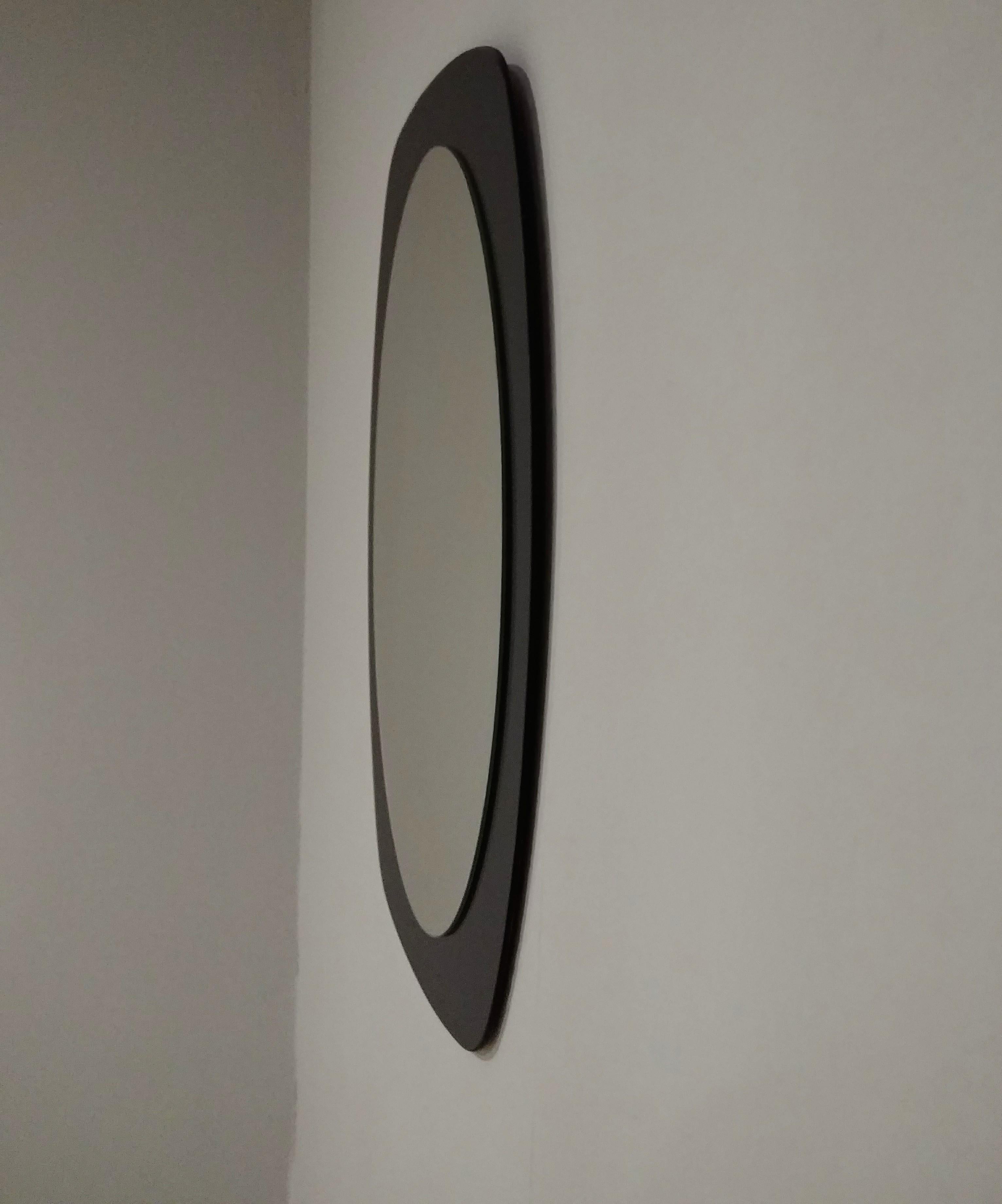 Oval-shaped mirror with square-shaped frame entirely in smoked glass. Italian production of the 1970s.