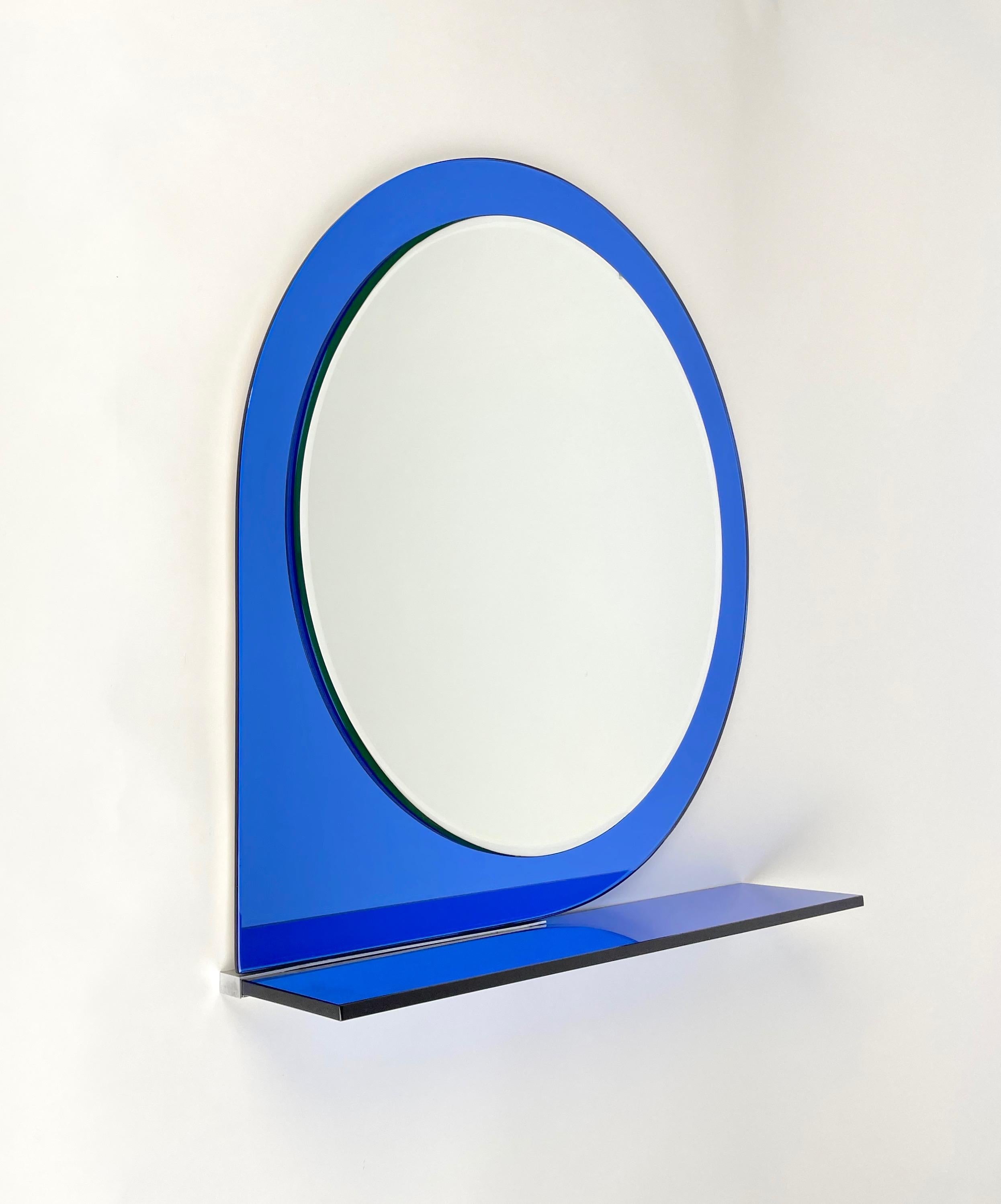 Wall mirror with shelf framed by blue glass by Sena Cristal. Made in Italy in 1974. 

The original label is still attached on the back of the mirror, as shown in the pictures.