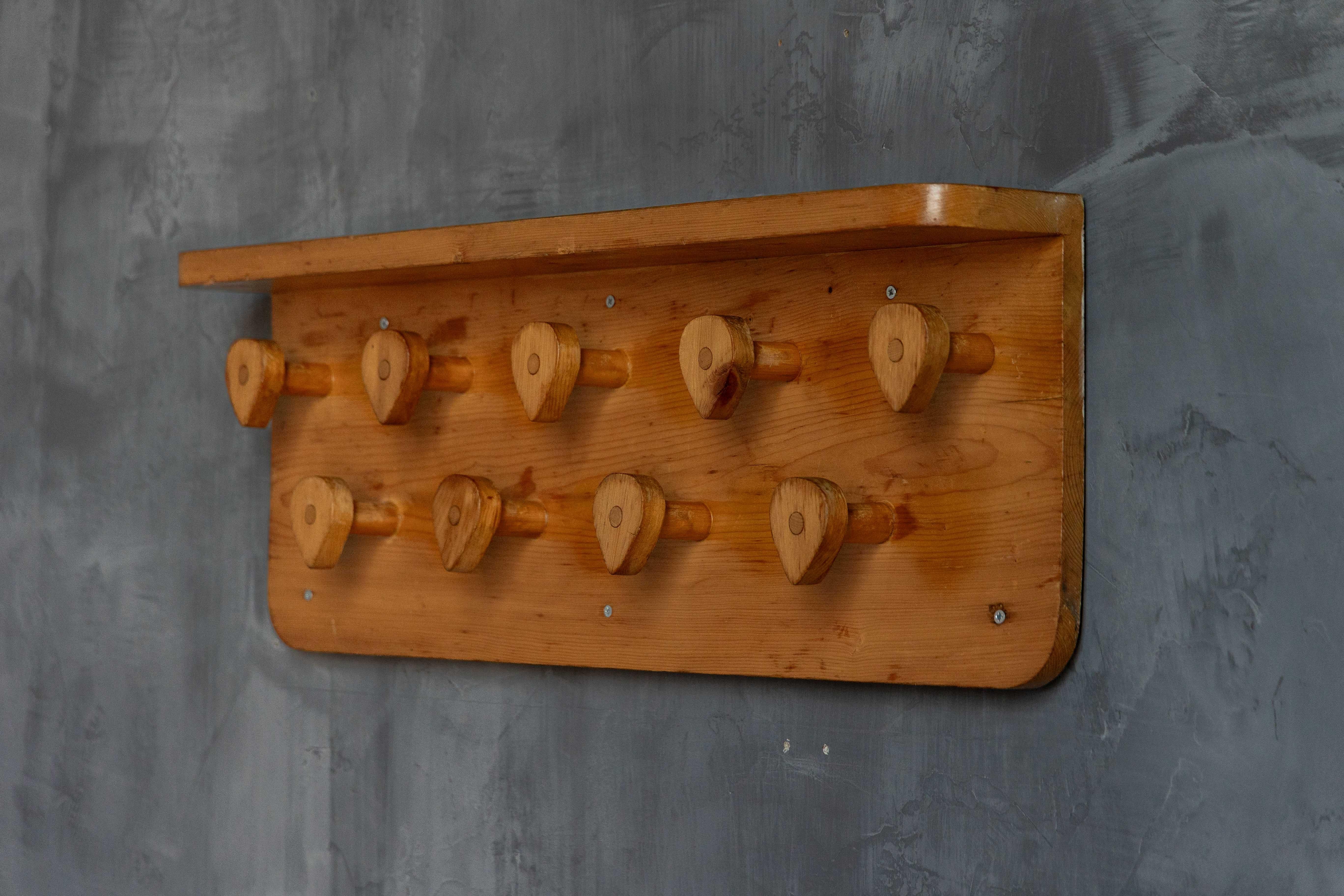 Inspiriert von schlichtem, zweckmäßigem Design und natürlichen Materialien, verkörpert diese Wandgarderobe den warmen, praktischen Stil, der Charlotte Perriands Werk ausmacht. Er ist aus Kiefernholz handgefertigt und hat neun skulpturale Zapfen, die