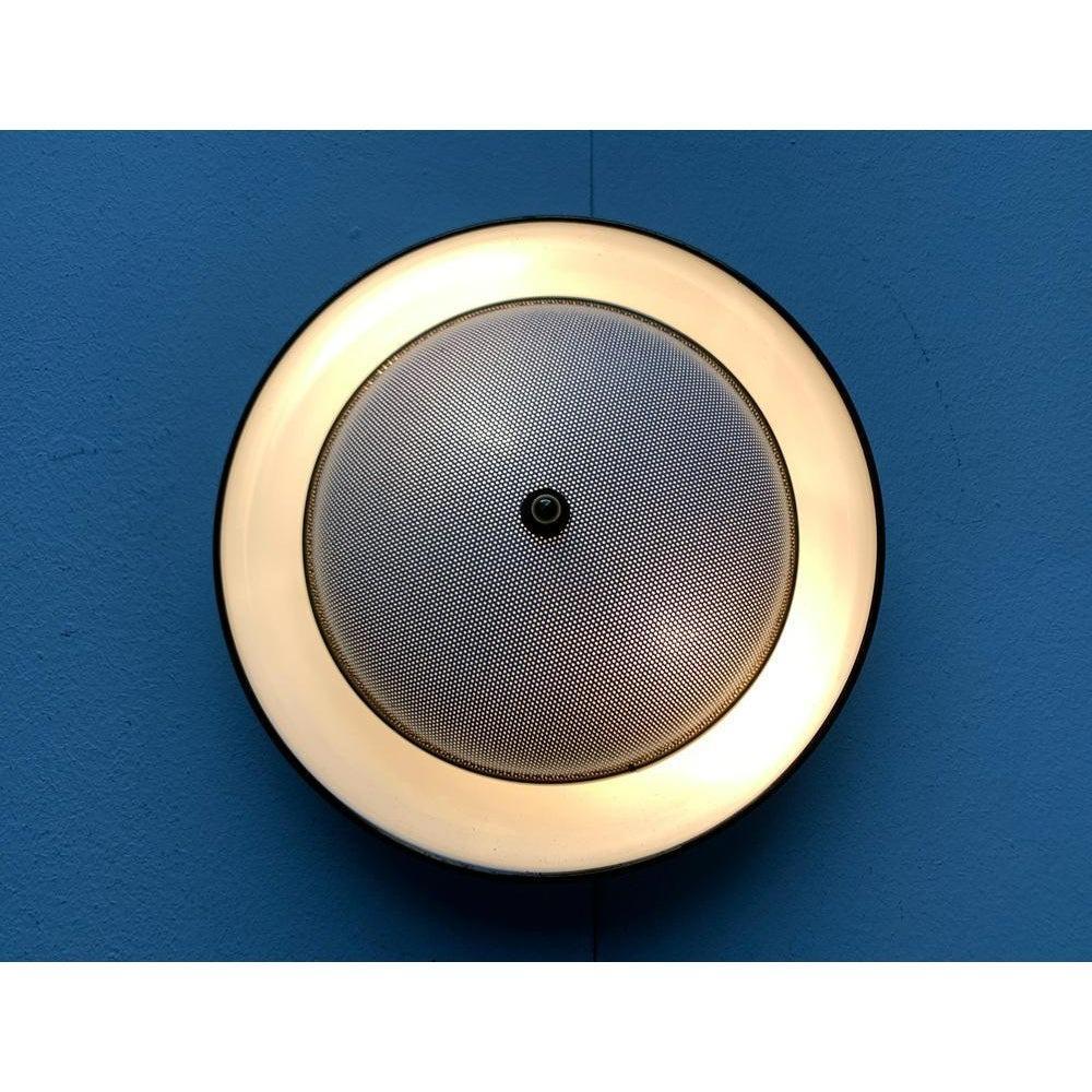 Imposante Mid Century Wand- oder Deckenleuchte.

Die Lampe besteht aus zwei Teilen. Die gebogene Reflektorwanne und der Diffusor an der Vorder- und Unterseite. Die Vorderseite schirmt die Lichtquelle ab und schützt vor Blendung. Gleichzeitig ist es