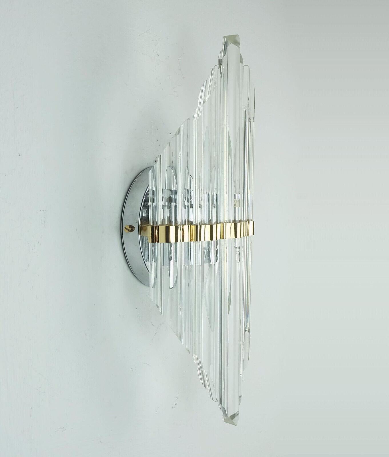 Stylish and glamorous vintage wall lamp from Spain. The wall bracket and support of the rods are made of chrome-plated or gold-colored metal, the shade is formed by solid glass rods of different lengths arranged in a fan-like manner. For 2 E14 light
