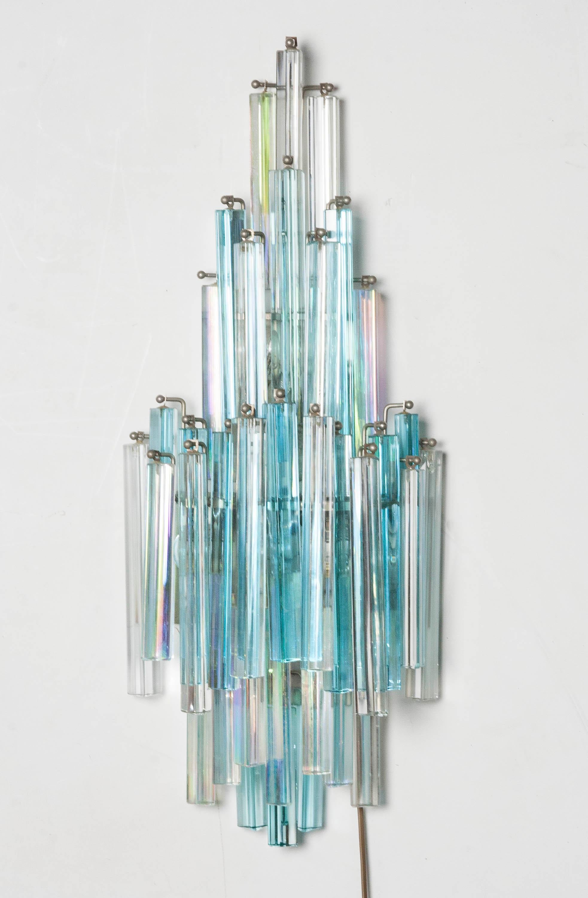 Beautiful Mid-Century Modern wall lamp decorated with crystal cones. Made circa 1970, Italy. Design by Paolo Venini (1895-1959). The lamp is hung with two color prism shaped cones, clear white and aquamarine blue. This lamp shines on all sides due