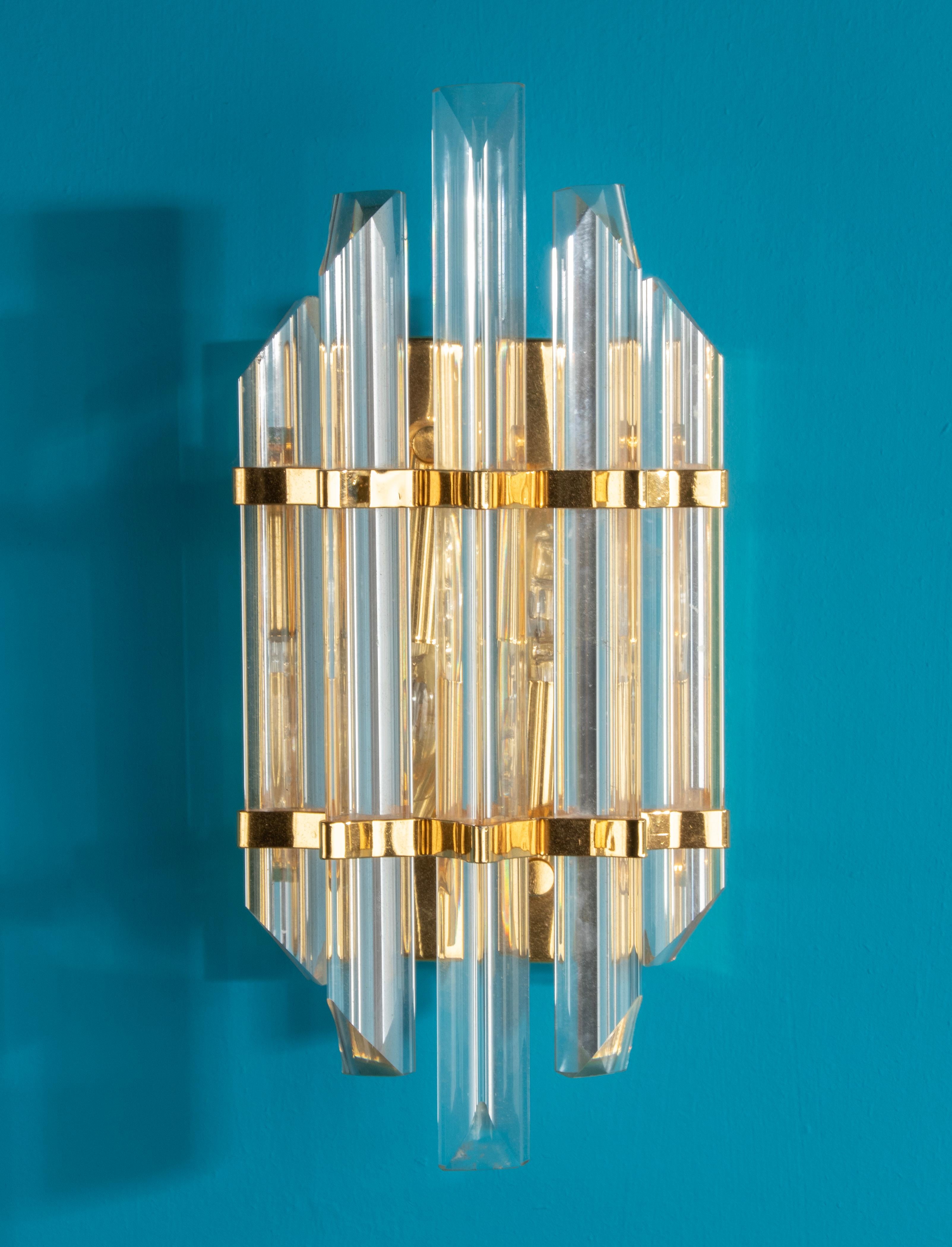 Beautiful Mid-Century Modern wall light, decorated with crystal prism shaped cones. Made in Italy, around 1960-1970. The fixture is made of metal with a brass polished finish.
When the light is on, this gives a beautiful and warm atmospheric