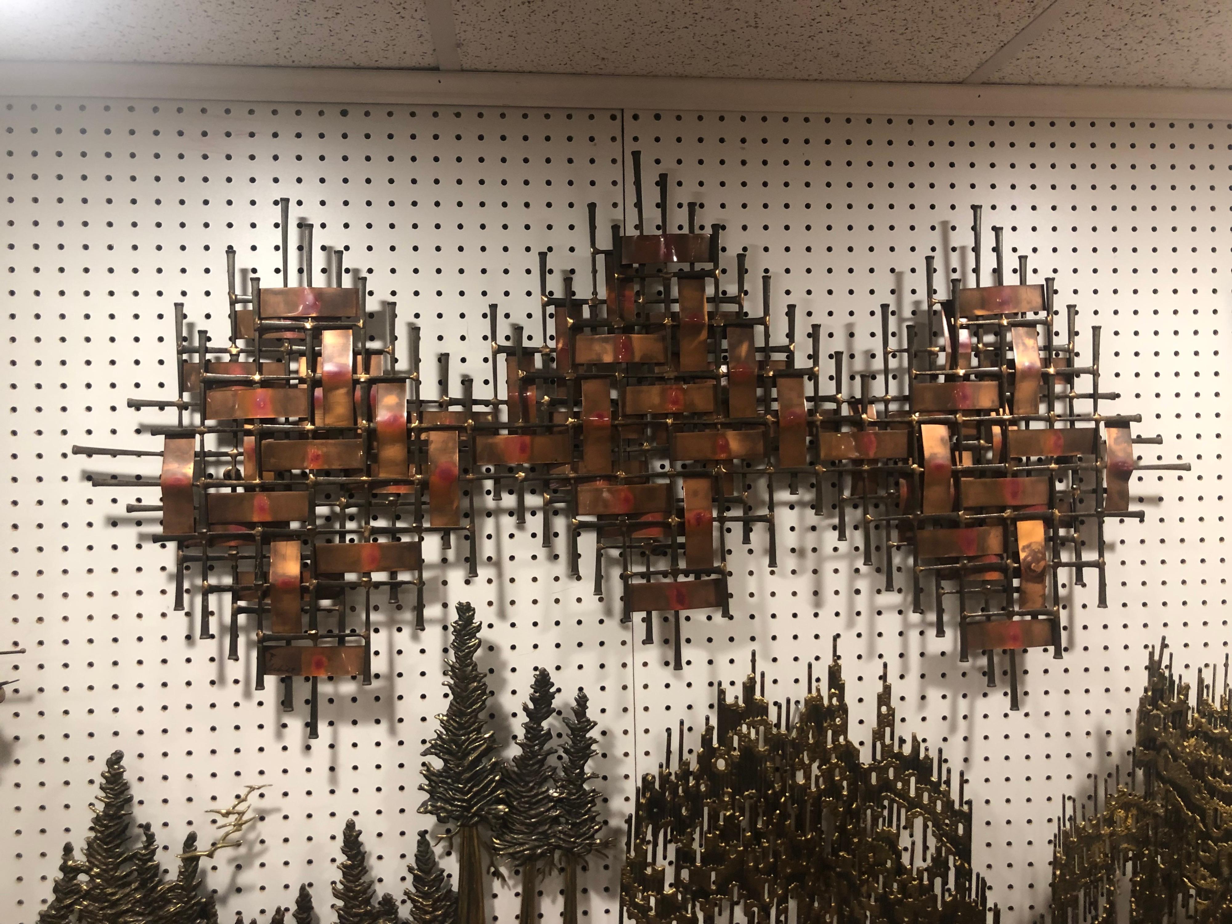 Mid century wall sculpture by Ron Schmidt. Weaved heavy mixed metal design. Accents of Red and black make up this beauty. This rich and textural sculpture would complement any room. Perfect size to hang above a headboard or fireplace mantle.