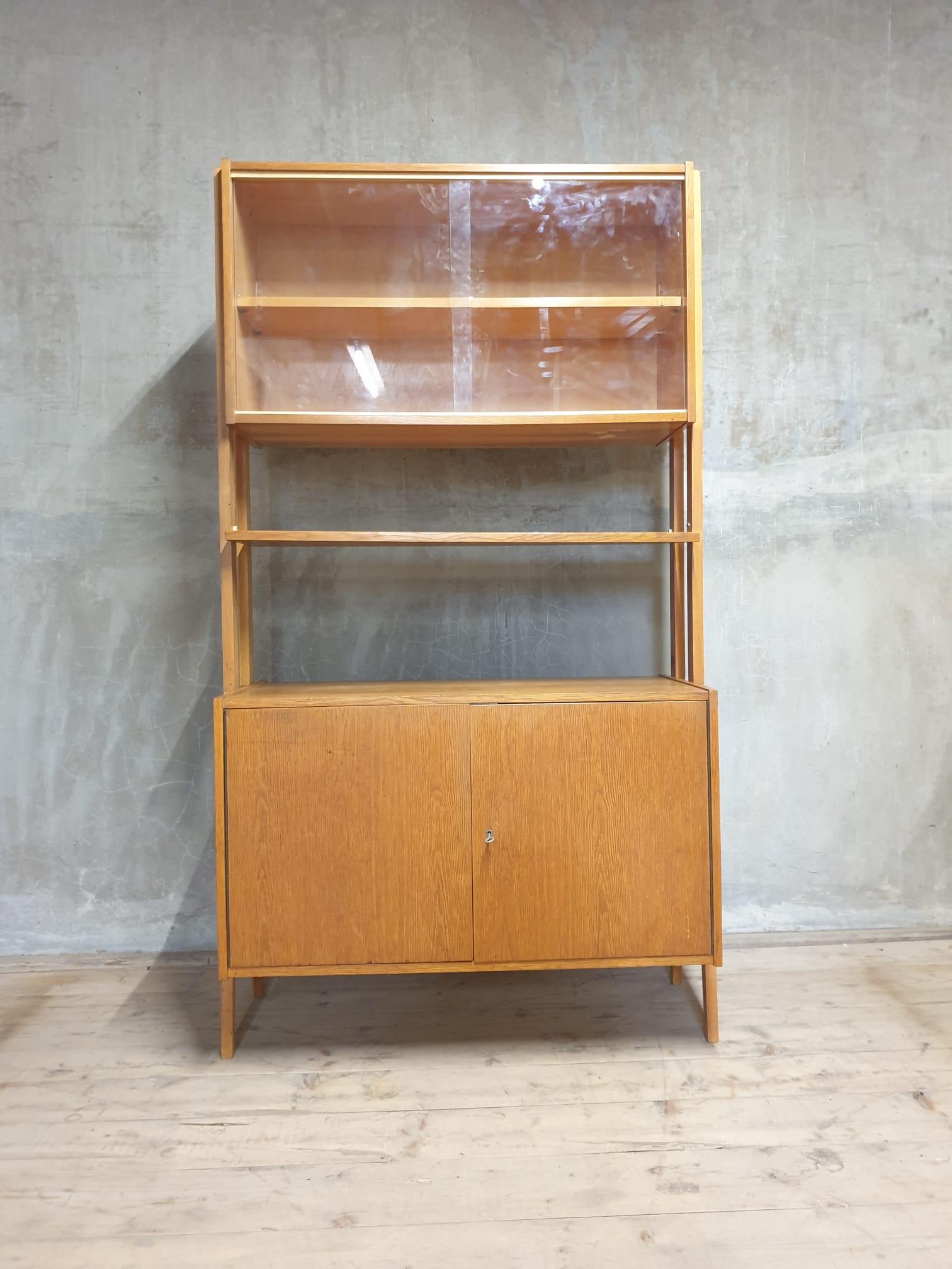 Mid century Vintage bookcase from the 1960´s. It was designed by František Jirák for Tatra nábytok in the former Czechoslovakia. Features a simple design, a glazed section with a storage space.

In very good Vintage condition, showing slight signs