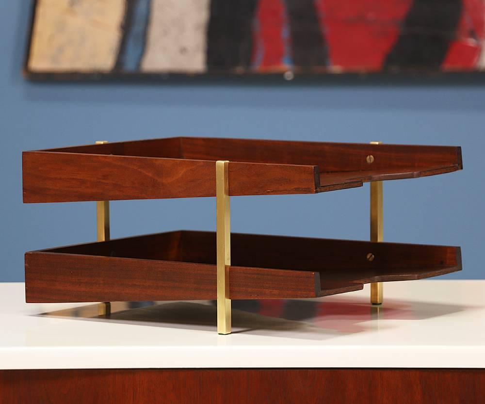 Mid-Century modern paper tray designed and manufactured in the United States c. 1960’s. A stylish and minimalist two-tier paper tray featuring clean lines and brass details that contrast beautifully with the brown color of the walnut wood. Item