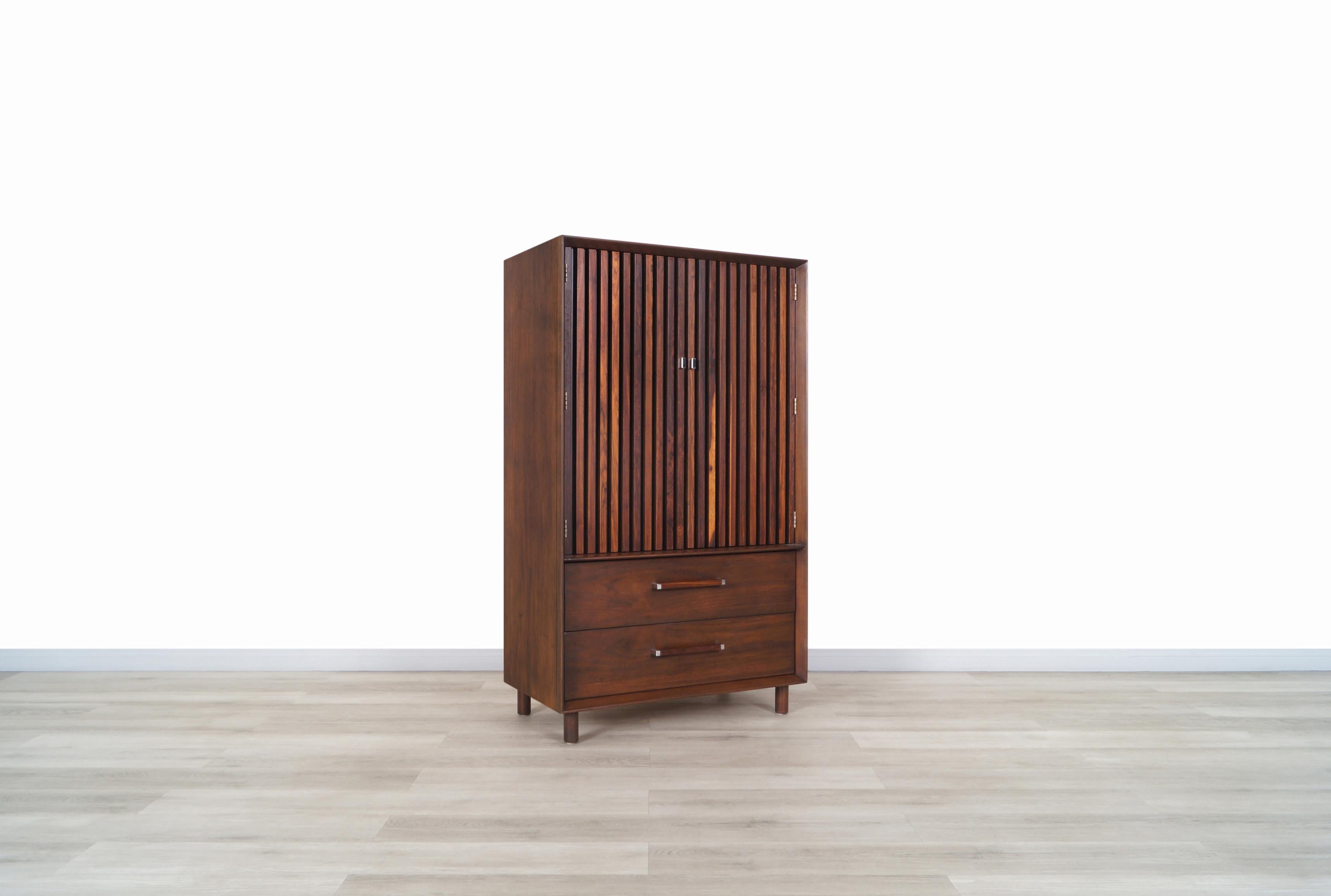 Wonderful mid century walnut and rosewood armoire manufactured by Lane Furniture in United States, circa 1970s. Features an innovative design where the blind-shaped doors stand out, allowing us to see the quality of the rosewood grains through its