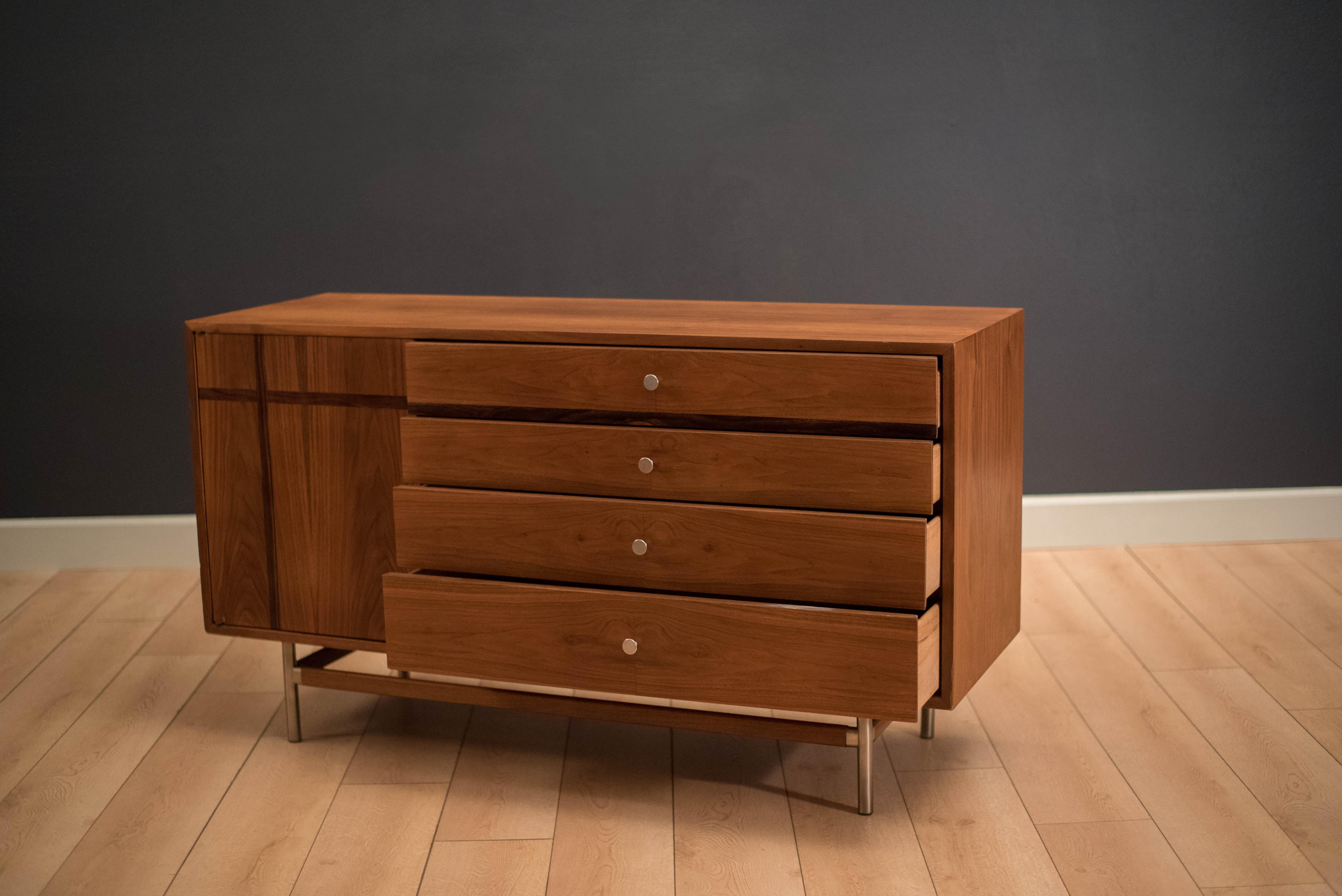 Mid-Century Modern dresser manufactured by Kroehler in walnut. The piece features rosewood inlay and aluminum accents. Equipped with four storage drawers and three additional drawers behind push door.

 
      