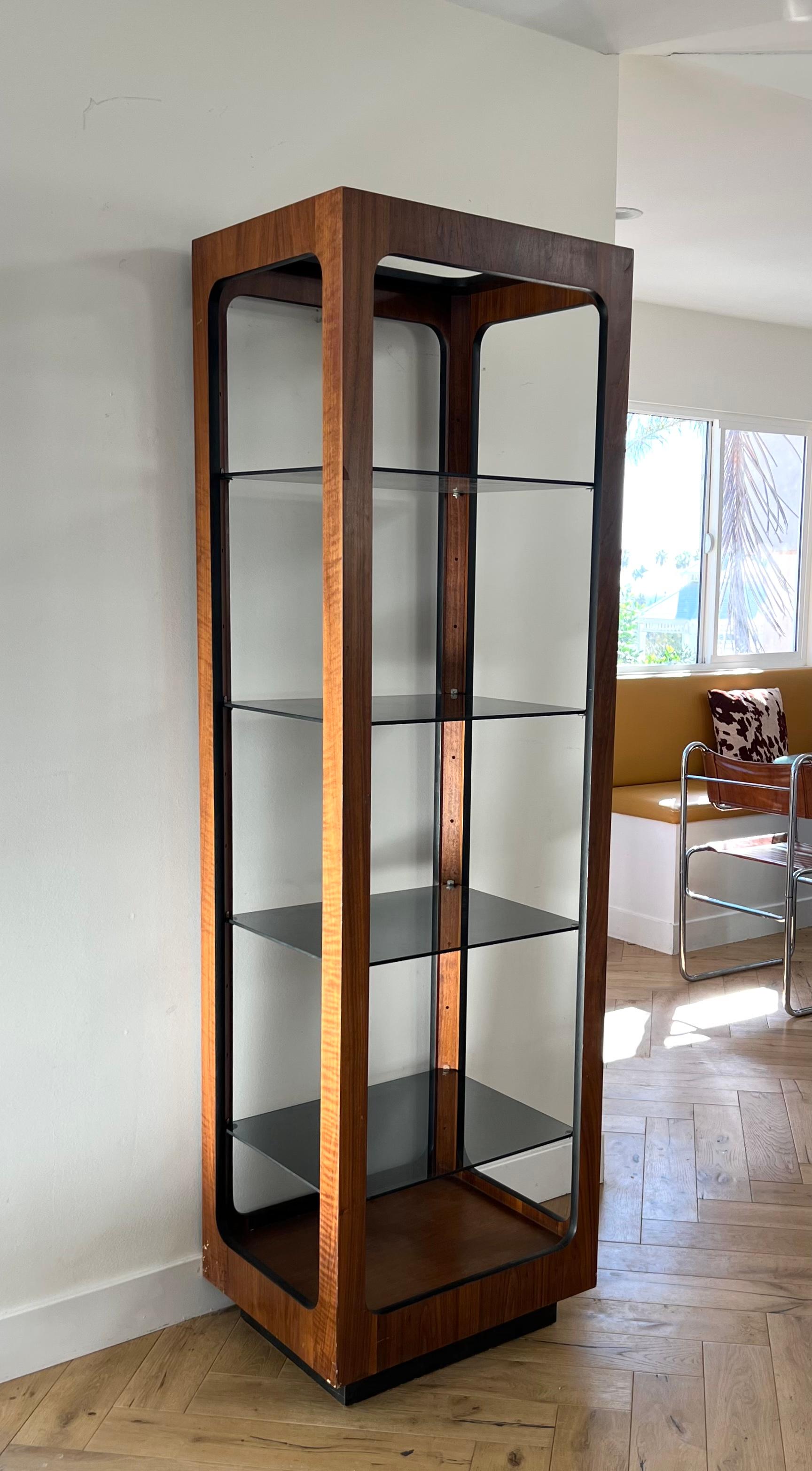 A Mid-Century Modern walnut and smoked glass étagère by Lane, early 1970s. A few nicks to veneer (as shown in photos) but otherwise great vintage condition. Glass shelves are removable for storage and transport. Pick up in central west Los Angeles