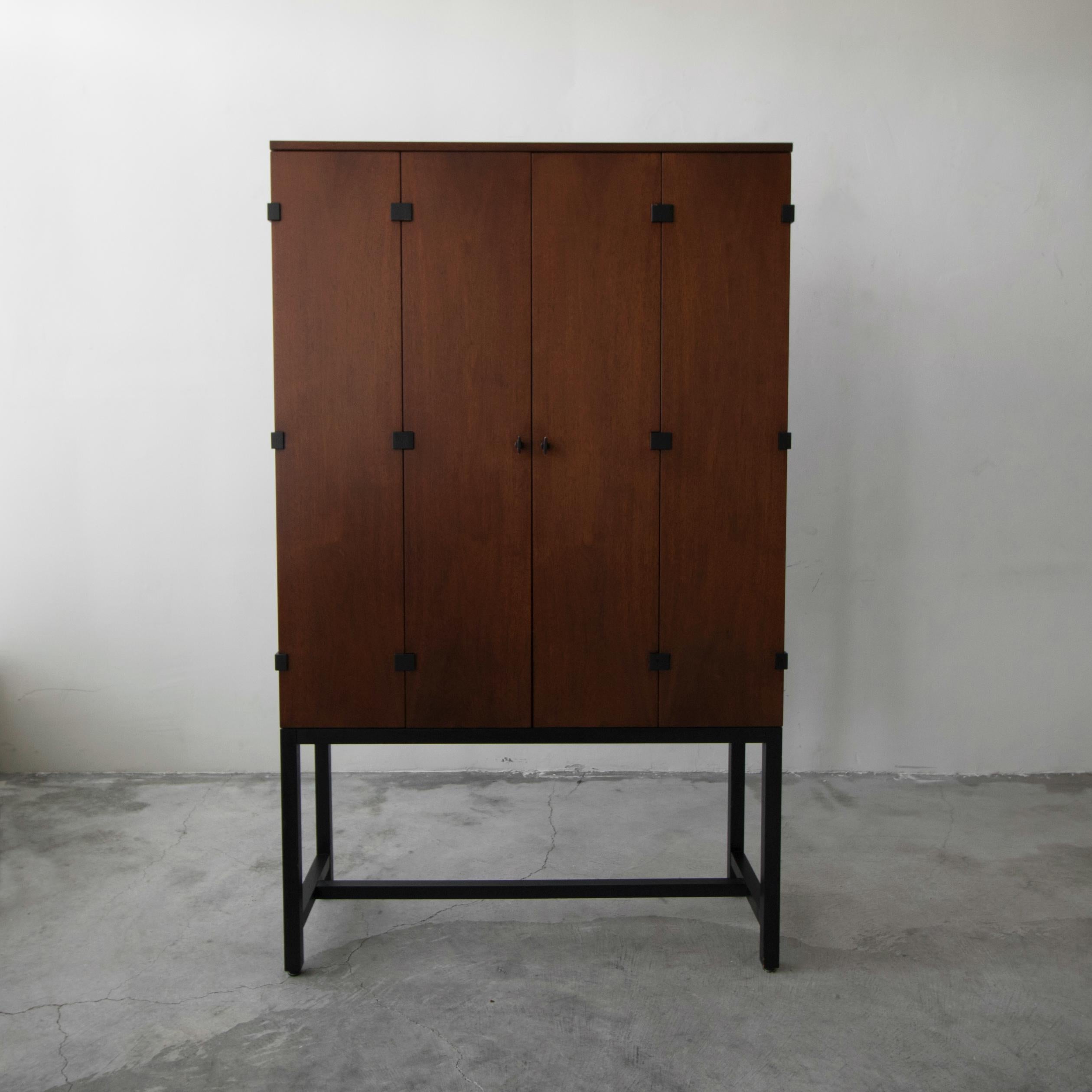 Beautiful midcentury walnut cabinet by Milo Baughman for Directional. Cabinet is beautiful walnut with black details, it features 2 bi-fold front doors with ample shelving and drawers inside for storage. A simple, vintage piece with modern appeal