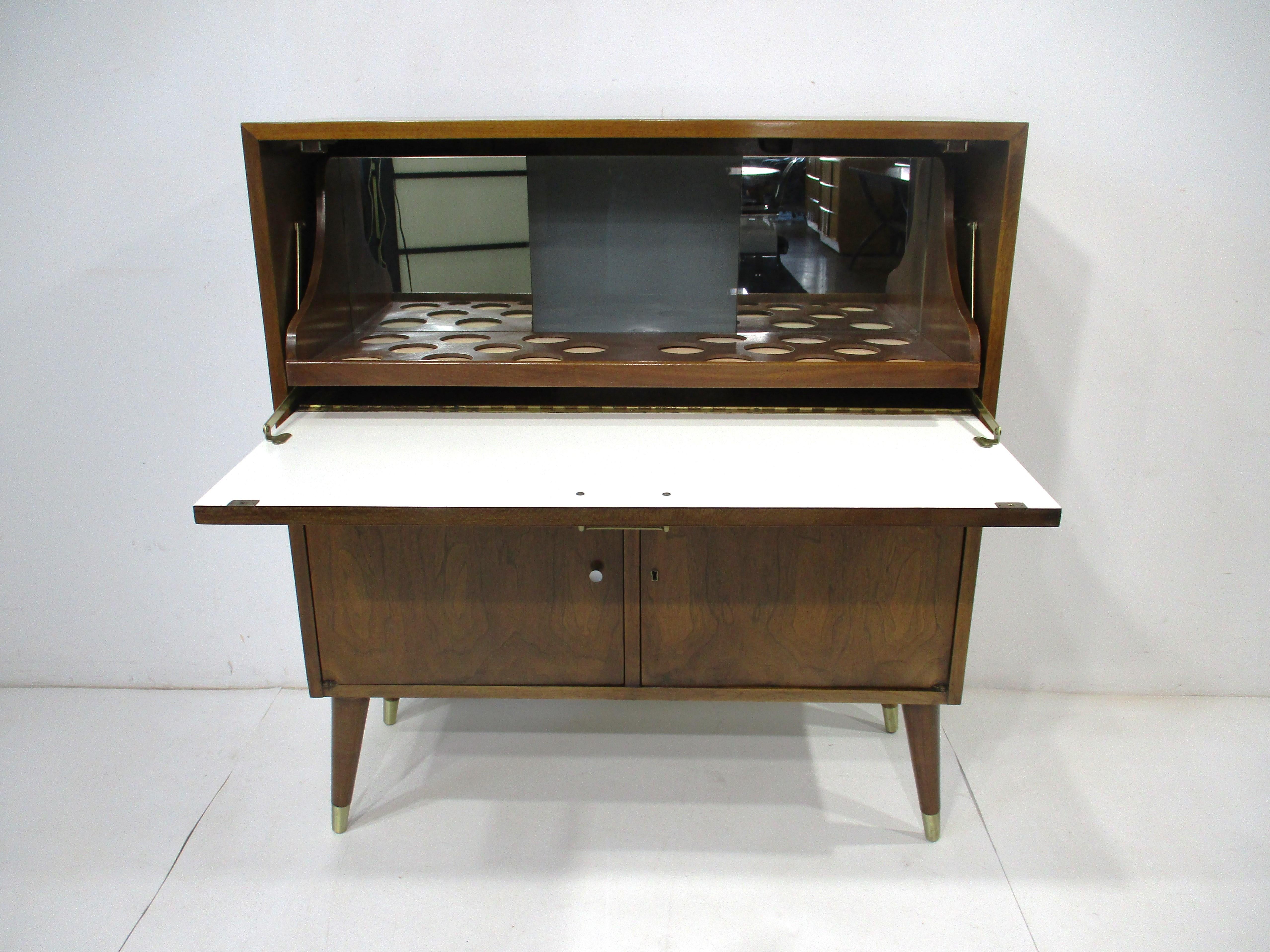 Un rare bar sec en noyer du milieu du siècle, avec une porte avant rabattable, un espace éclairé pour les boissons et un espace de rangement pour les verres. Whiting, la porte est revêtue d'un stratifié blanc, ce qui en fait une surface de bar pour