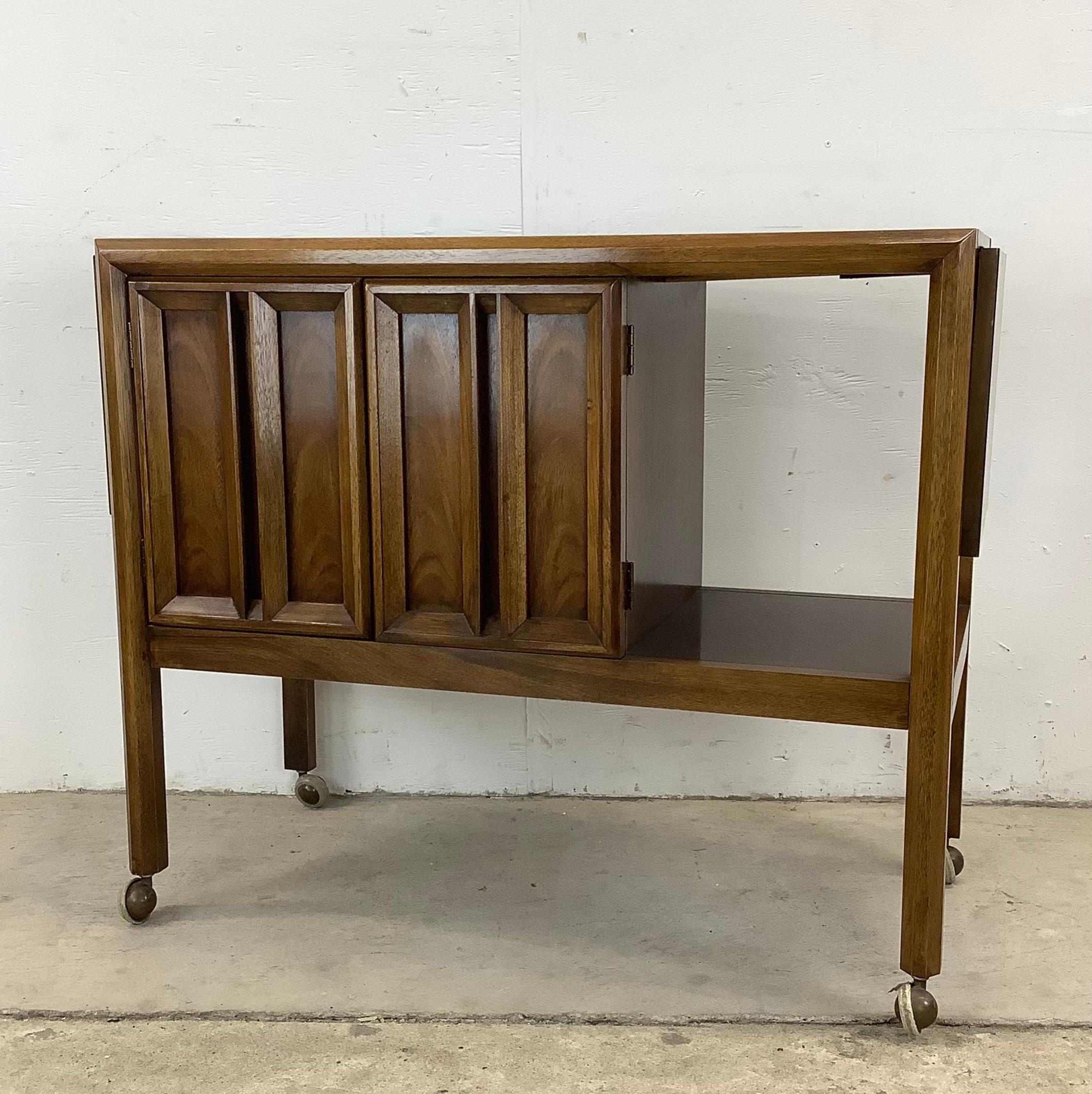 This Mid-Century Walnut Bar Cart is a stylish and versatile piece that's ready to elevate your style and service game to the next level. Combining versatile storage, display, and service options with a sleek mid-century aesthetic, it makes the