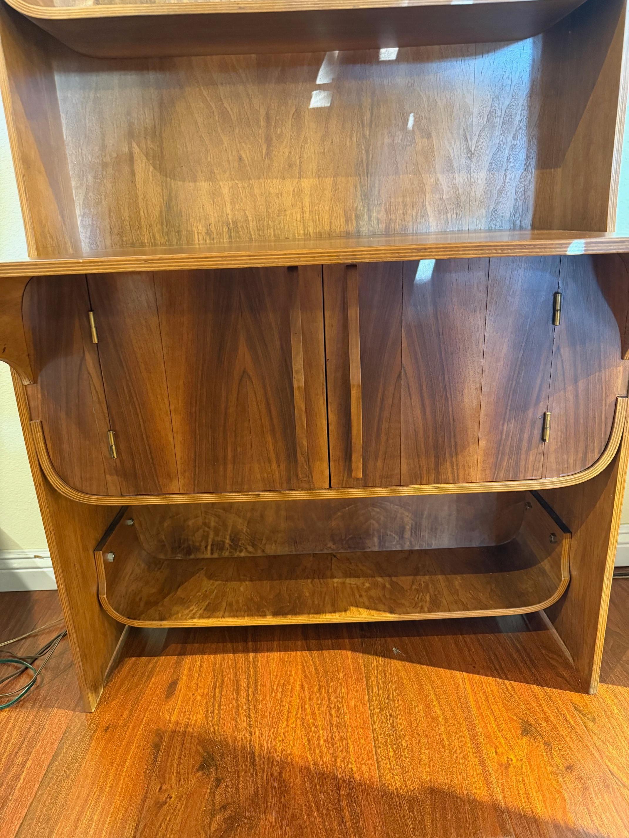 Made of richly grained walnut, this elegant mid-century bookcase, crafted in the Dyrlund style, features softly rounded corners and fluid lines, with shelves that seem to curve outward in a gentle, rhythmic movement. At the base, a cabinet with