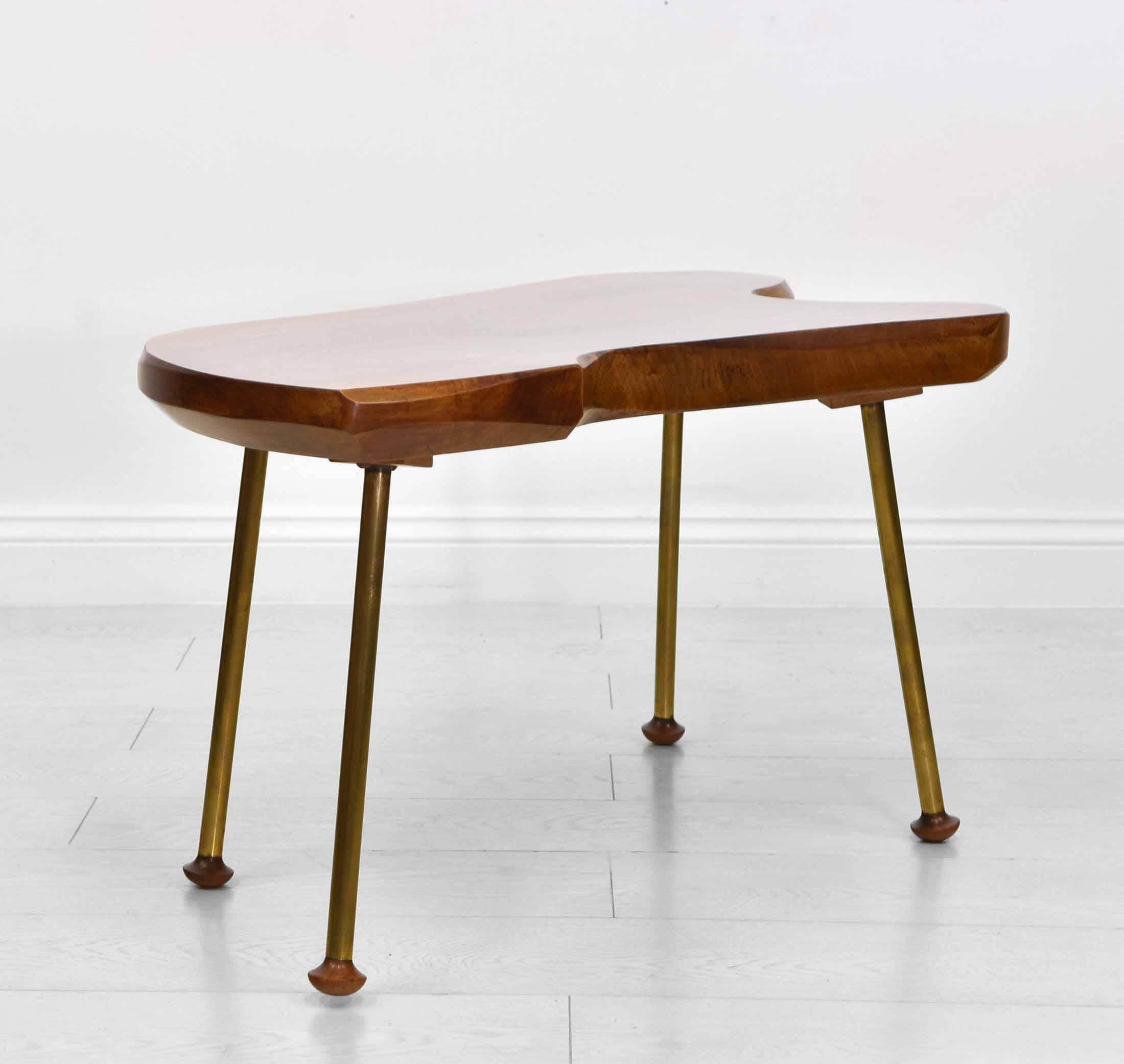 A walnut and brass coffee table in the Carl Auböck style. Circa 1950s.

Free UK delivery.

The table has a solid crown shaped walnut top, terminating on brass tubular legs with teak turned feet.

Overall in very good condition for its age, the top