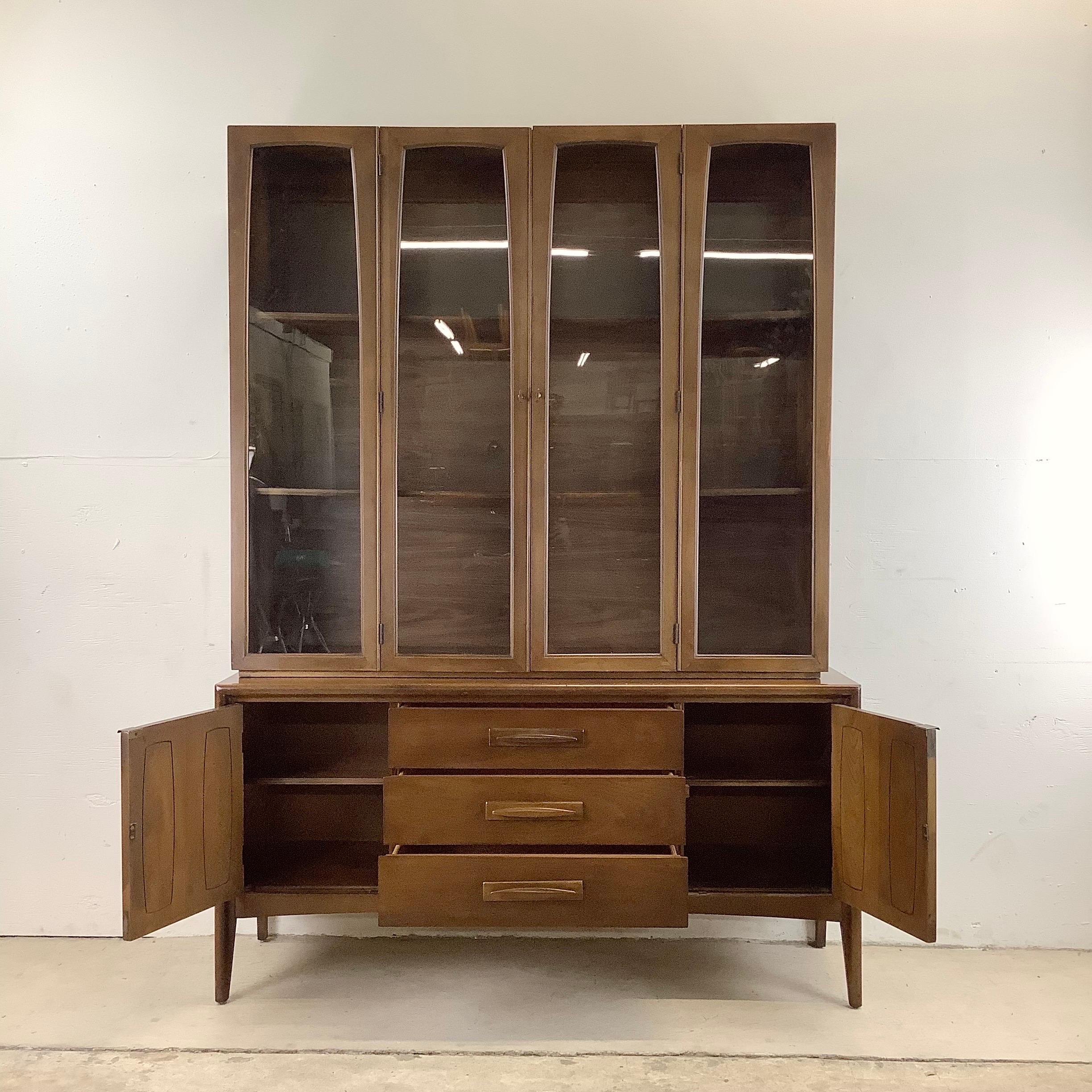 This stylish midcentury sideboard with china cabinet display top features sculpted drawer pulls and features plenty of storage and display space. This two piece sideboard from Broyhill makes an impressive statement piece perfect for home or business