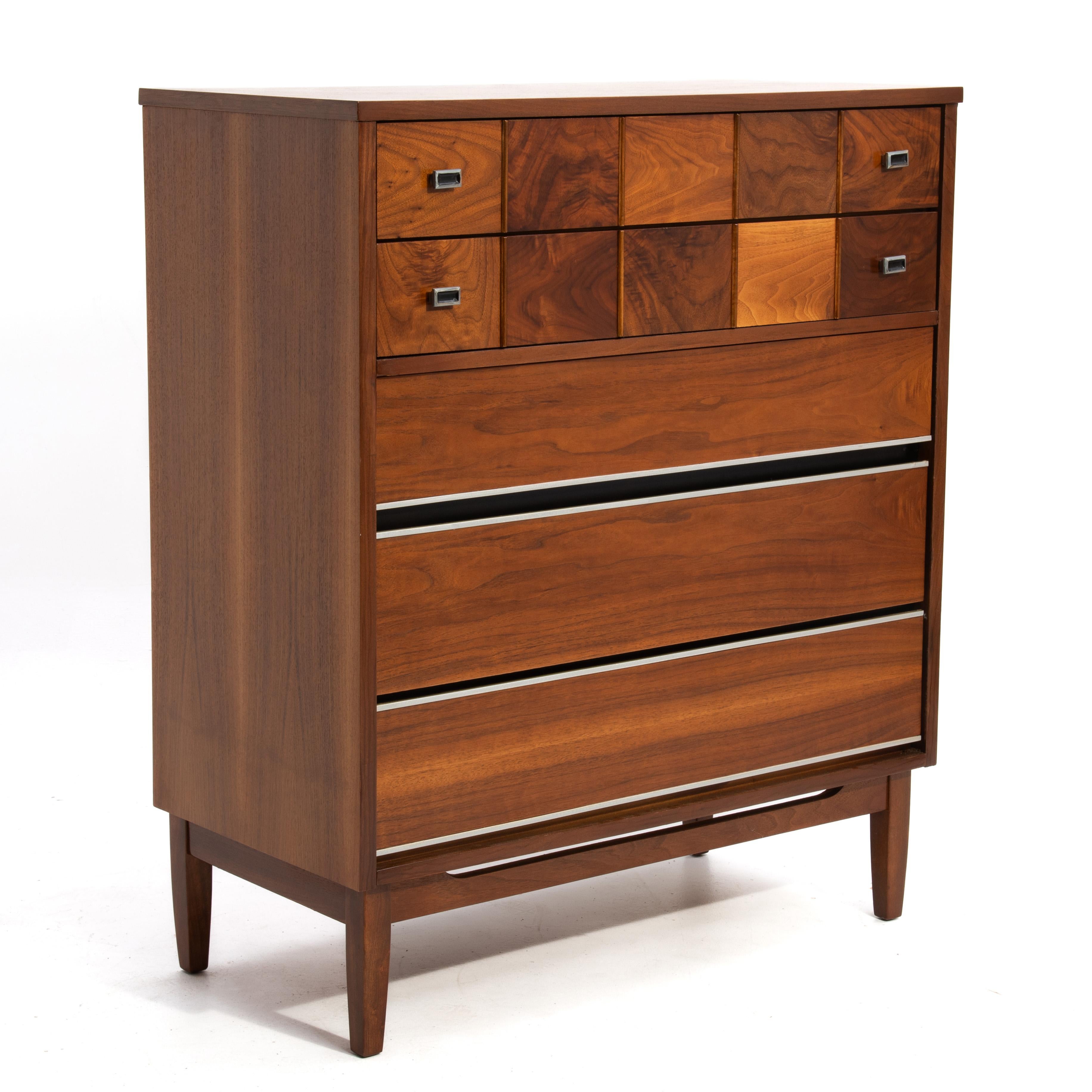 A beautiful American Modern Mid-Century walnut chest. Unmarked and by an unknown maker the chest has ten burl panels on the top drawer with four rectangular knobs. The lower three drawers have blind pulls either on the top or underside of the