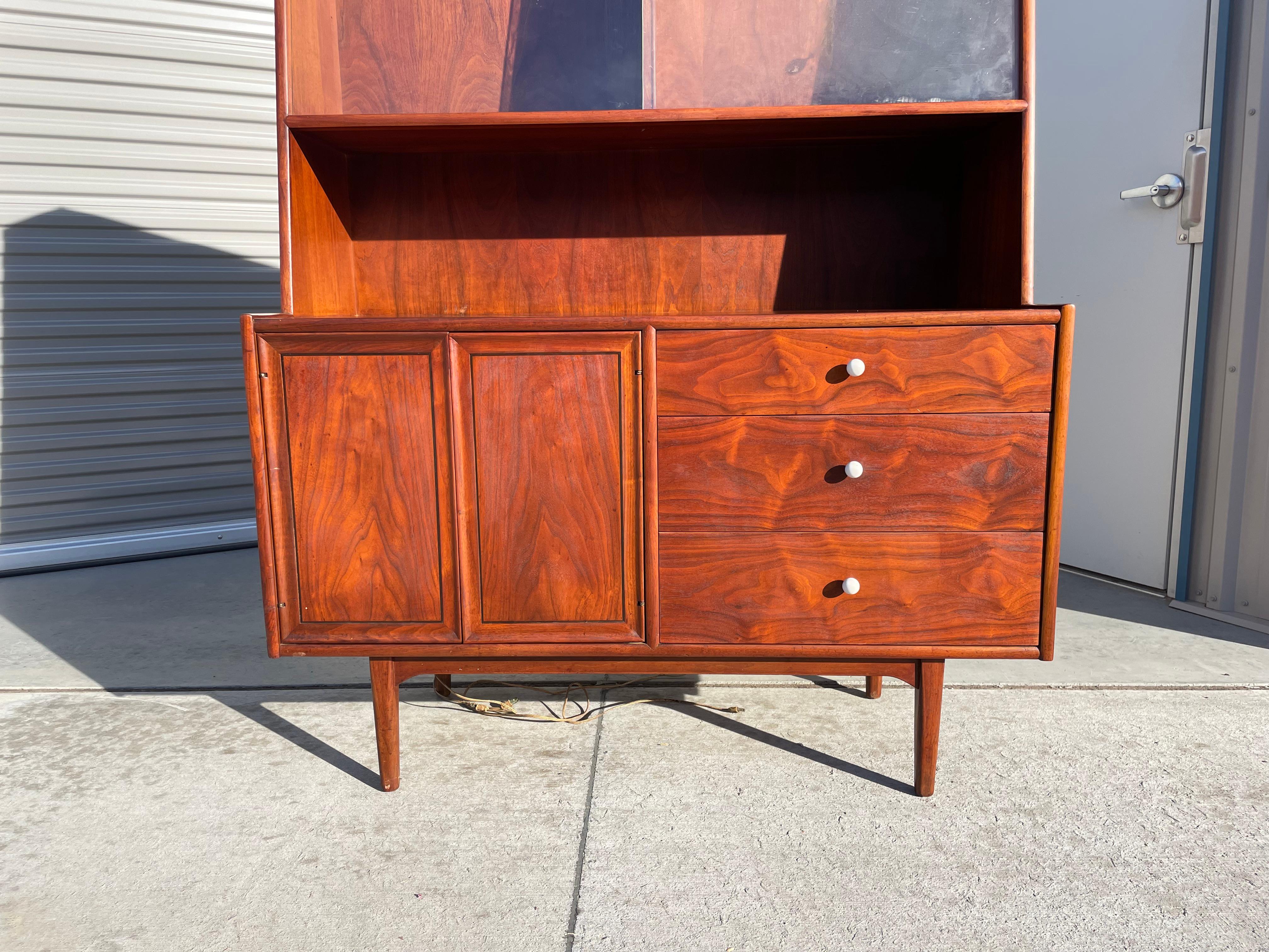 Midcentury walnut cabinet designed by Kipp Stewart for Drexel in the United States circa 1950s. This vintage cabinet features a lower section with three large storage drawers, each with Kipp Stewart signature white porcelain handles. The left side
