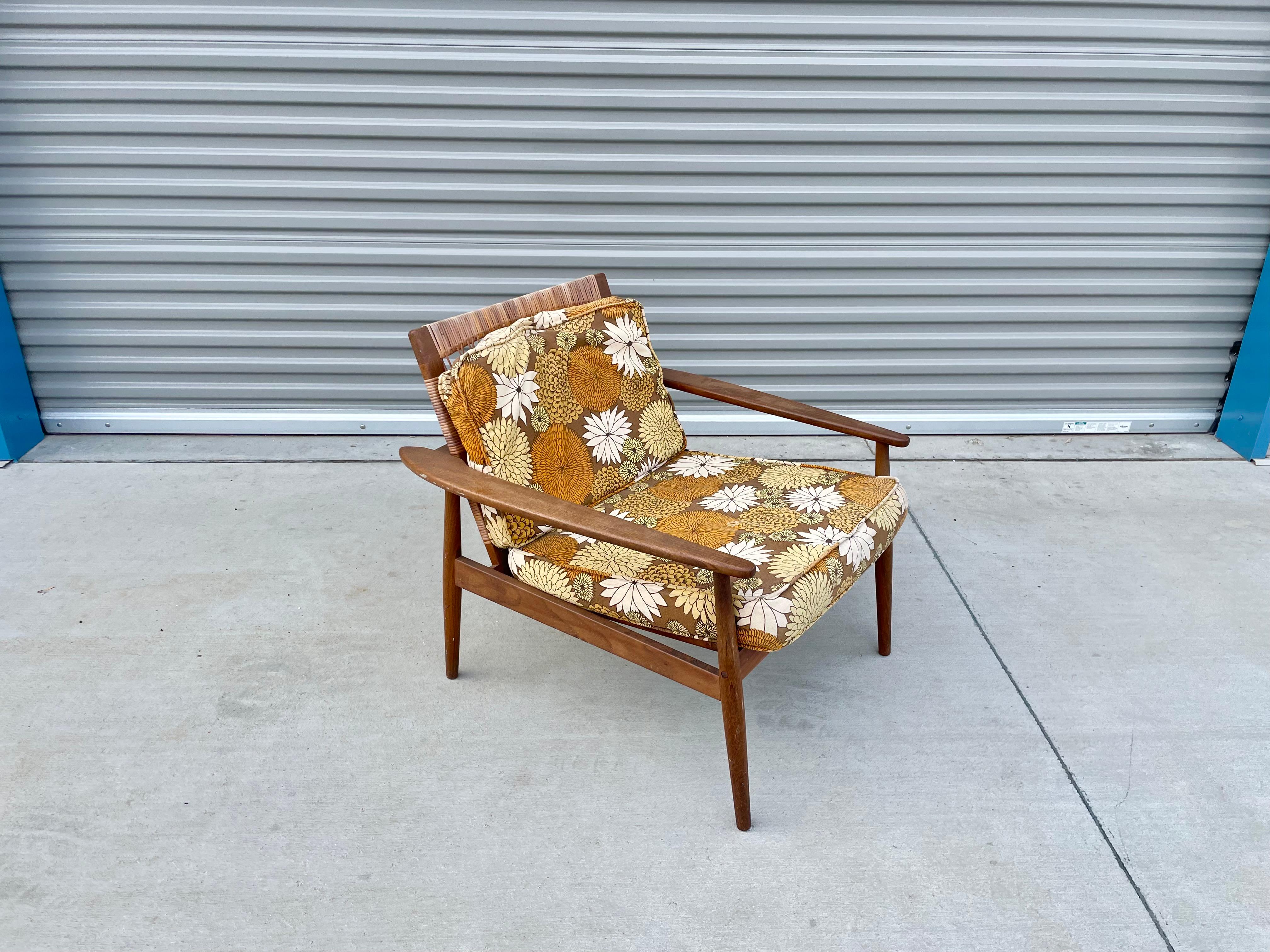 Midcentury walnut cane lounge chair styled after Hans Olsen designed and manufactured in the United States circa 1960s. This beautiful lounge chair features a solid walnut frame with an excellent color tone and a beautiful grain pattern creating a