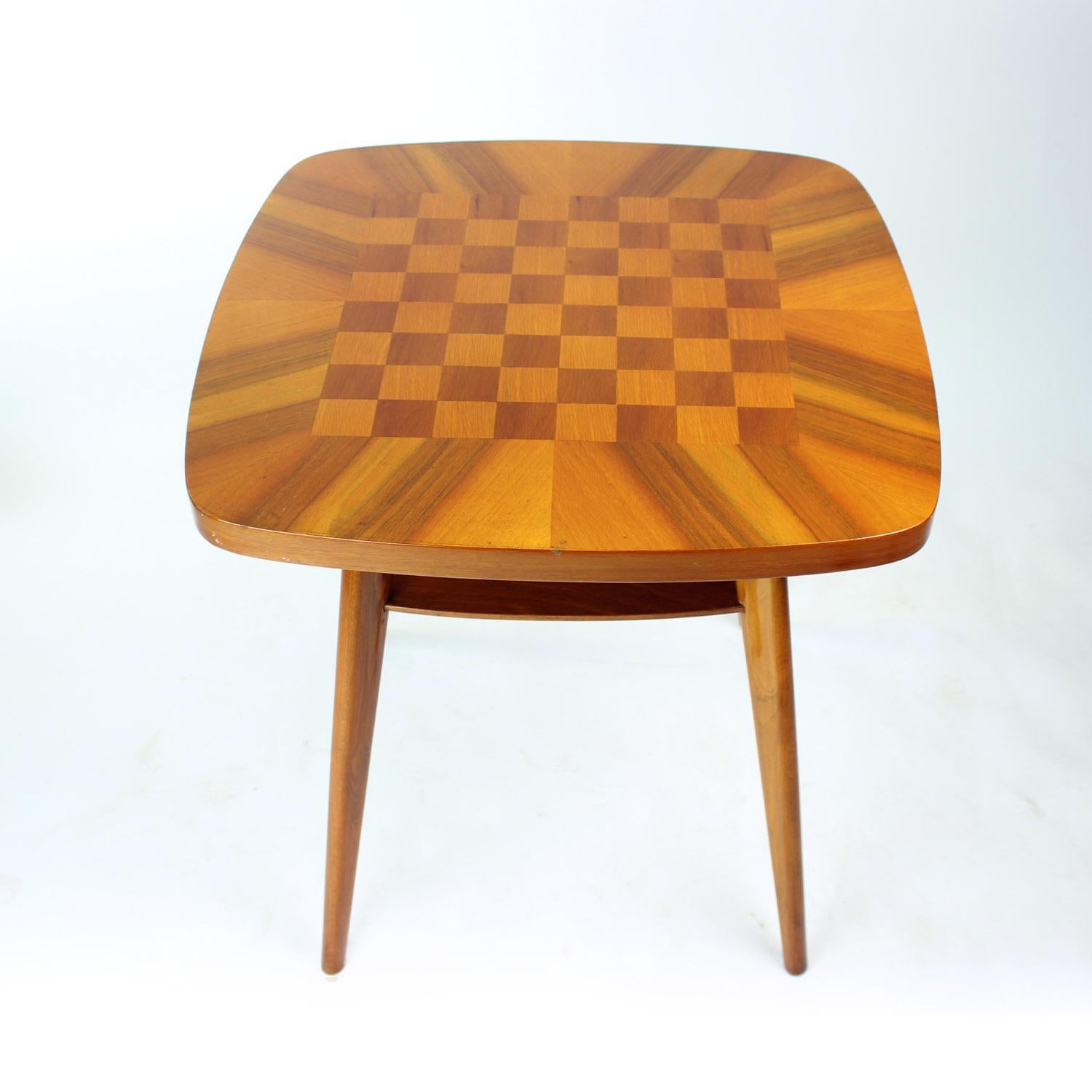 A striking example of mid-century craftsmanship, this elegant chess coffee table was produced in Czechoslovakia in the 1960s. Expertly crafted from rich walnut wood, the piece features a lustrous, high-sheen finish that highlights the natural grain