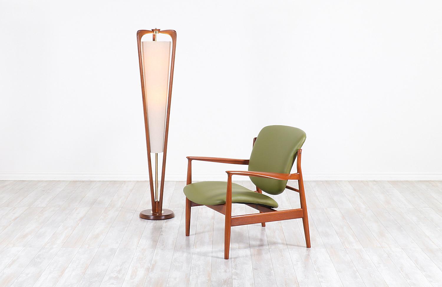Vintage modern floor lamp designed and manufactured in the United States, circa 1960s. This elegant Mid-Century Modern lamp features a tall and solid walnut wood frame with a stunning grain detail throughout adding a warm flair to any room. The base