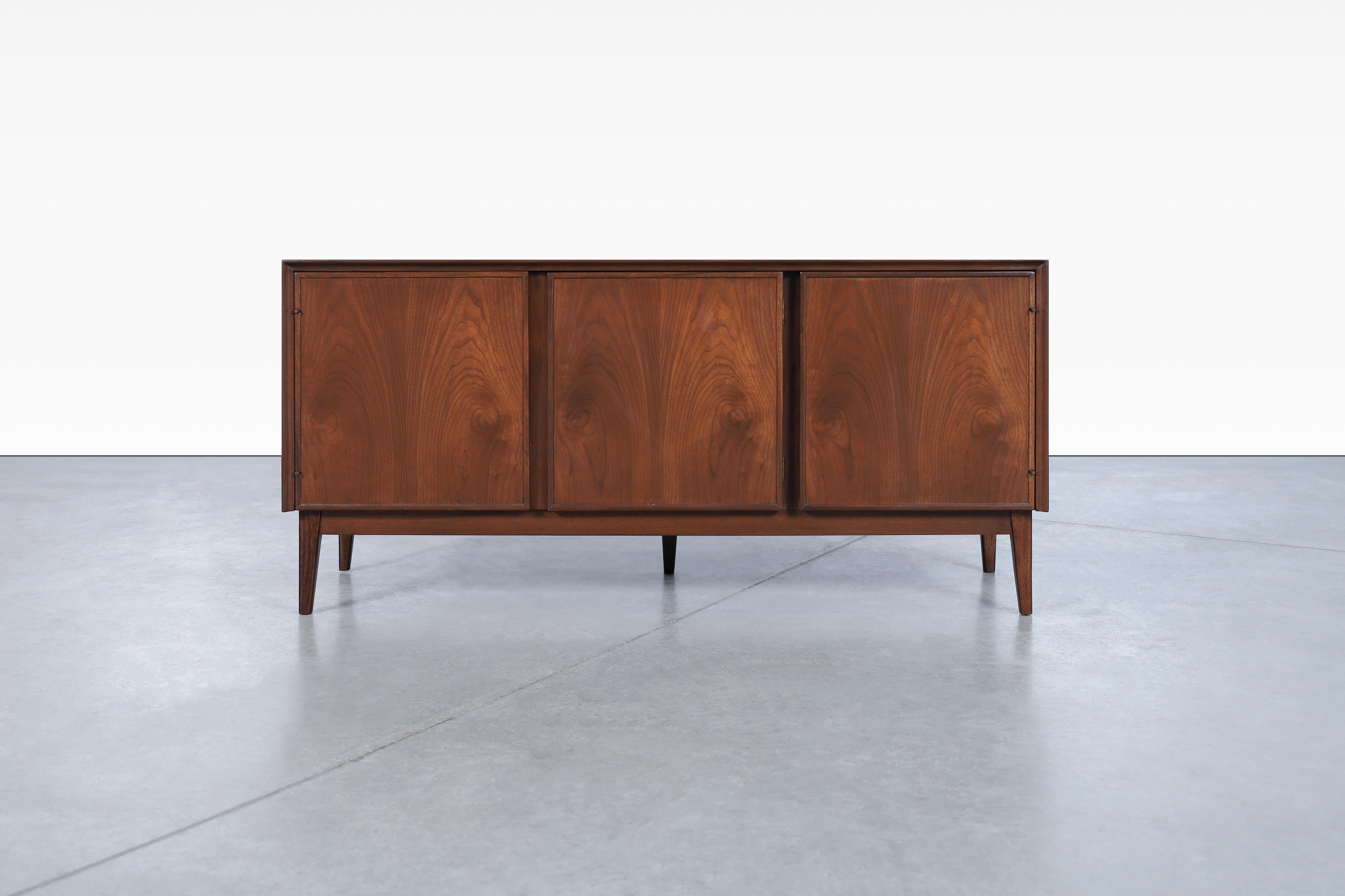 Amazing mid-century modern walnut credenza by Merton L. Gershun for American of Martinsville and manufactured in the United States, circa 1960s. This piece showcases the perfect blend of form and function, embodying the essence of mid-century modern