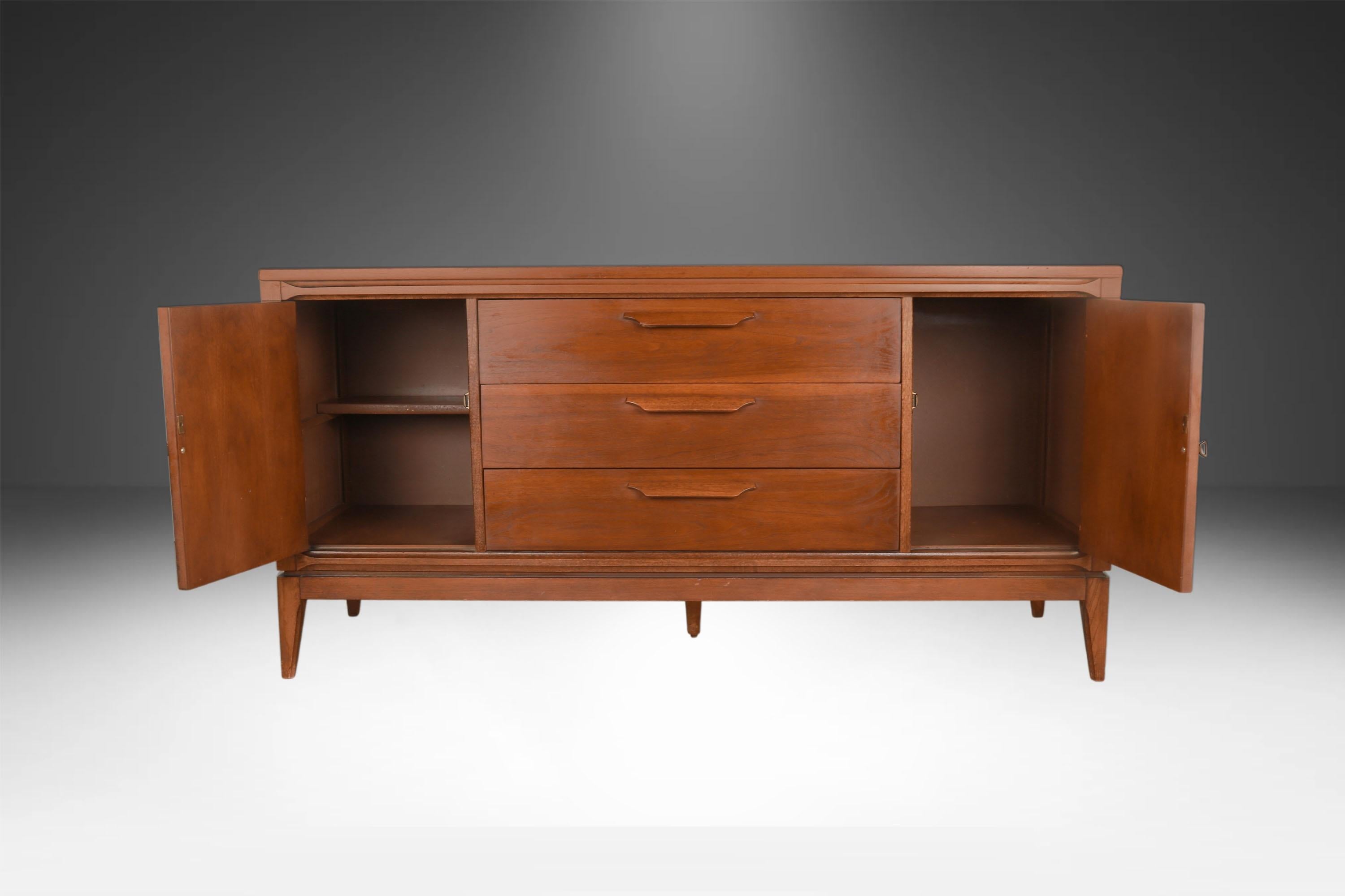 Bellissima credenza Bassett di metà secolo, cassettiera degli anni '60 circa. Caratterizzato da un piano rettangolare in noce splendidamente rifinito che sovrasta tre spaziosi cassetti al centro e due armadietti sui lati destro e sinistro. Il mobile