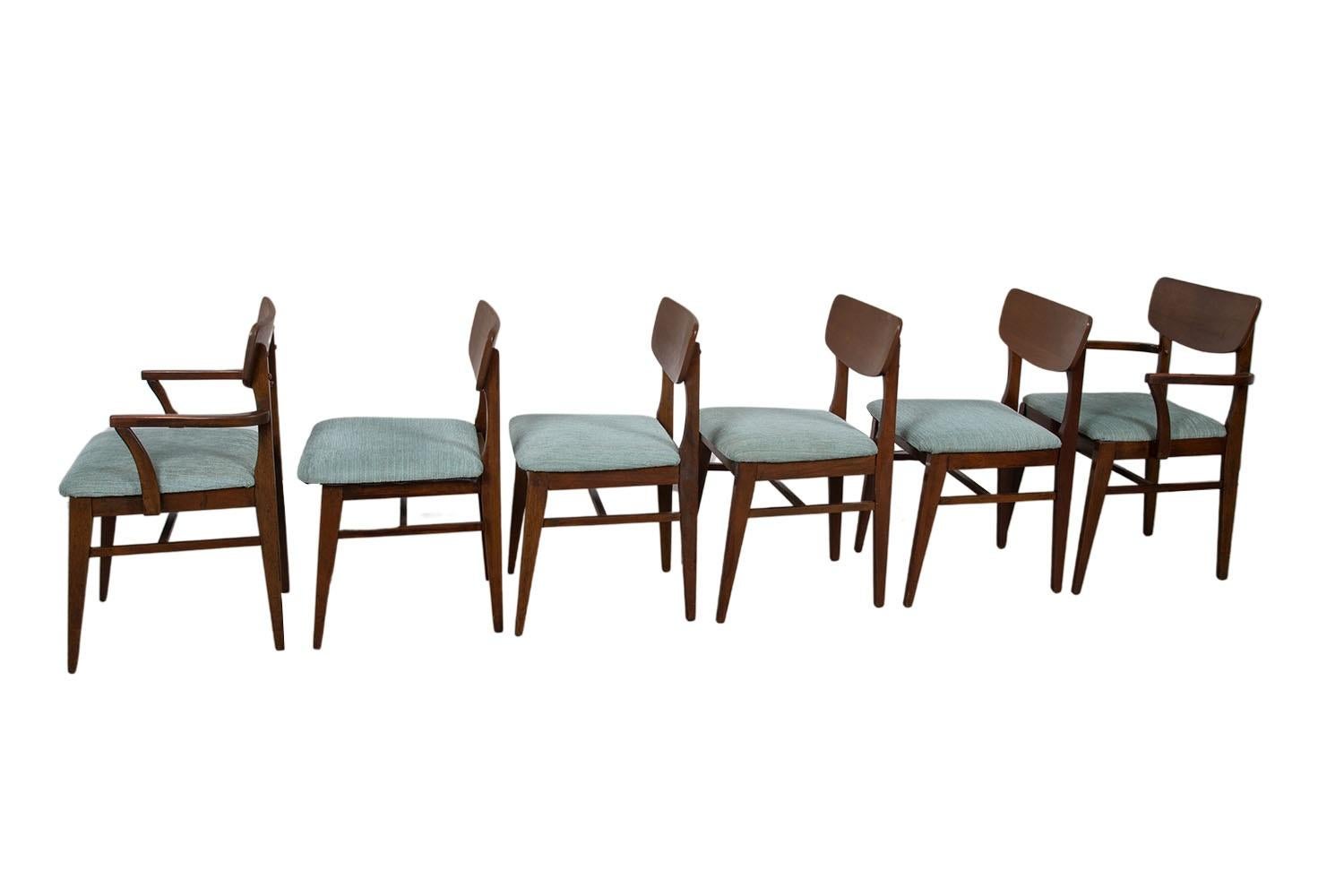 Set of six stunning Mid-Century Modern Walnut dining chairs, two armchairs and four side chairs. The walnut frames feature modern styling with a distinct beautiful design. Sculpturally carved backrests with tapered legs. Rich warm walnut frames with
