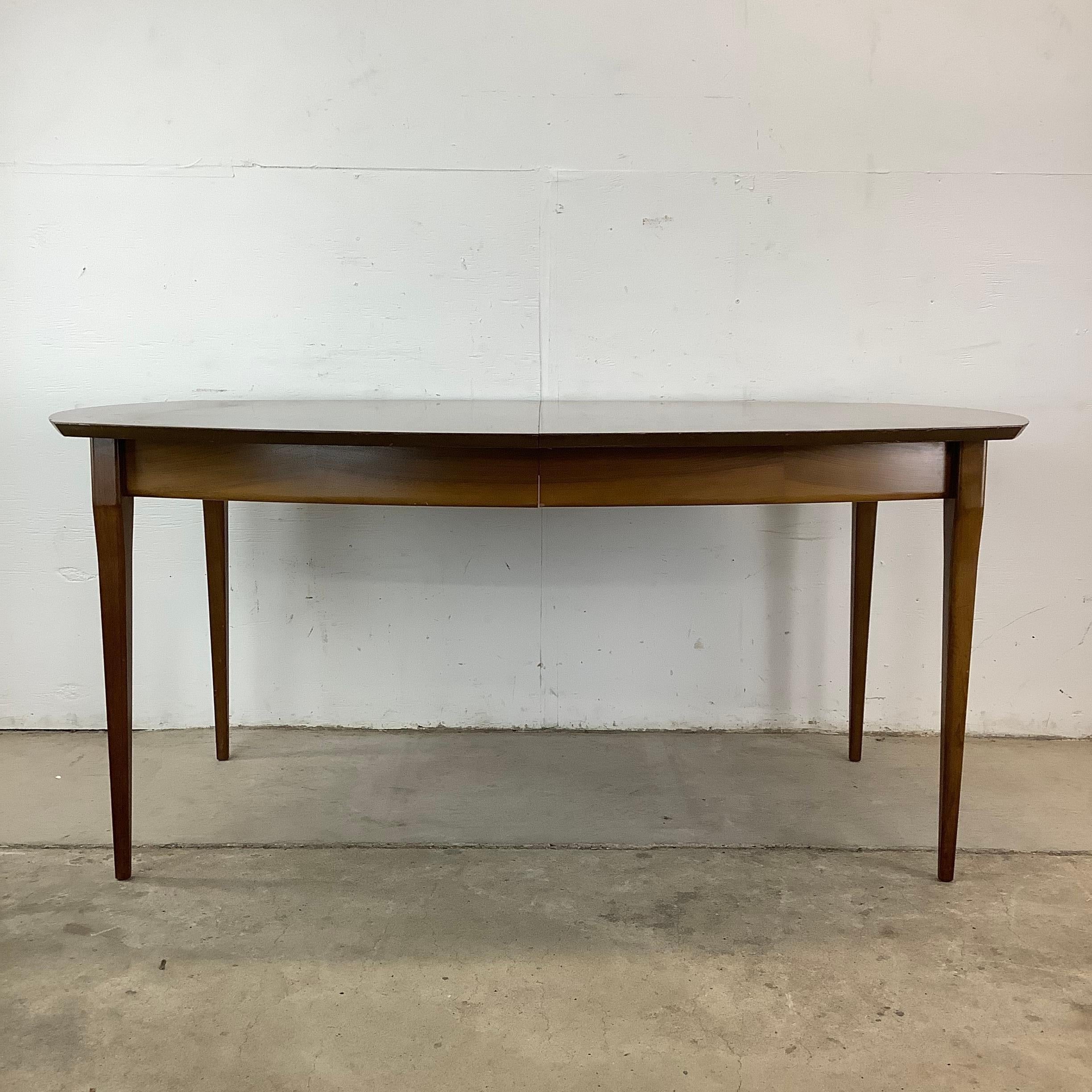 Embrassez l'allure durable du design du milieu du siècle avec cette exquise table de salle à manger en noyer, une pièce qui reflète le raffinement classique et l'attrait intemporel. Son design présente des lignes épurées et élégantes qui ont été