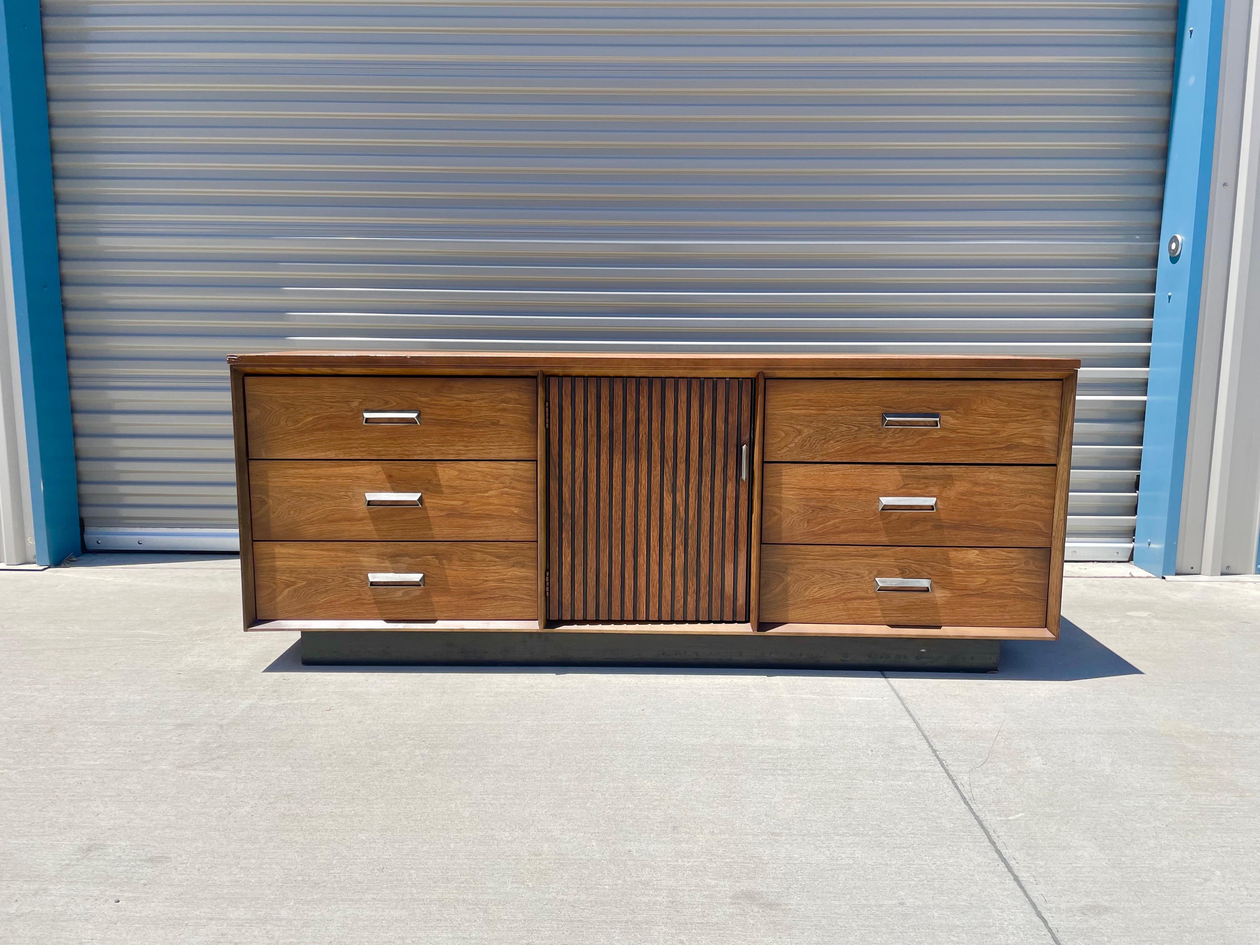 Mid-century walnut dresser this beautiful walnut dresser was manufactured by Bassett Furniture. It features six drawers with aluminum handles and one pull-out door, reviling three extra drawers for extra space.