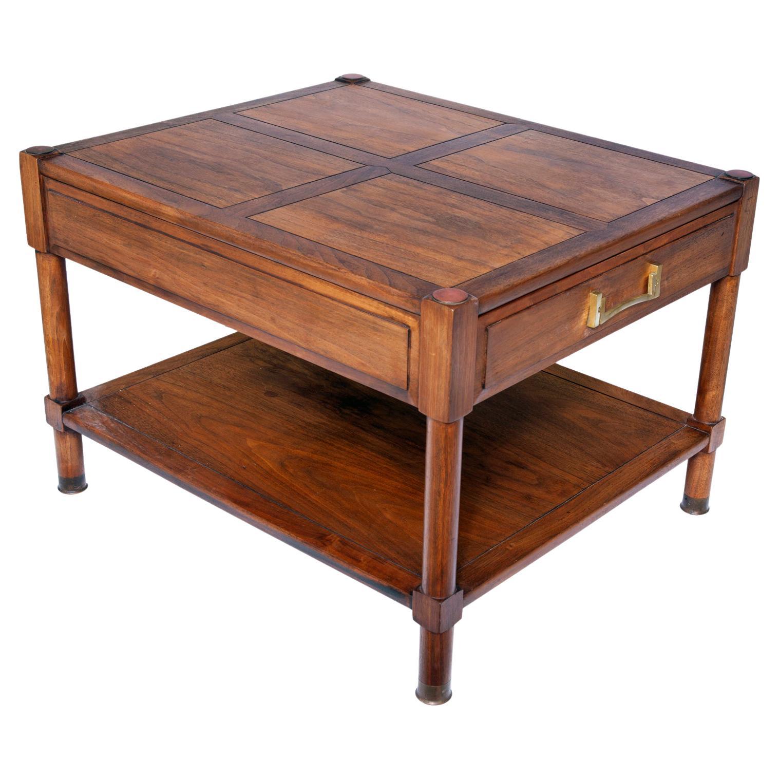 Classic mid-century walnut side tables by Heritage. Each table with unique brass hardware & a single drawer & a lower shelf. 
The feet are capped in brass, the lower shelf sits close to the floor.
Restored in a rich warm brown user friendly finish