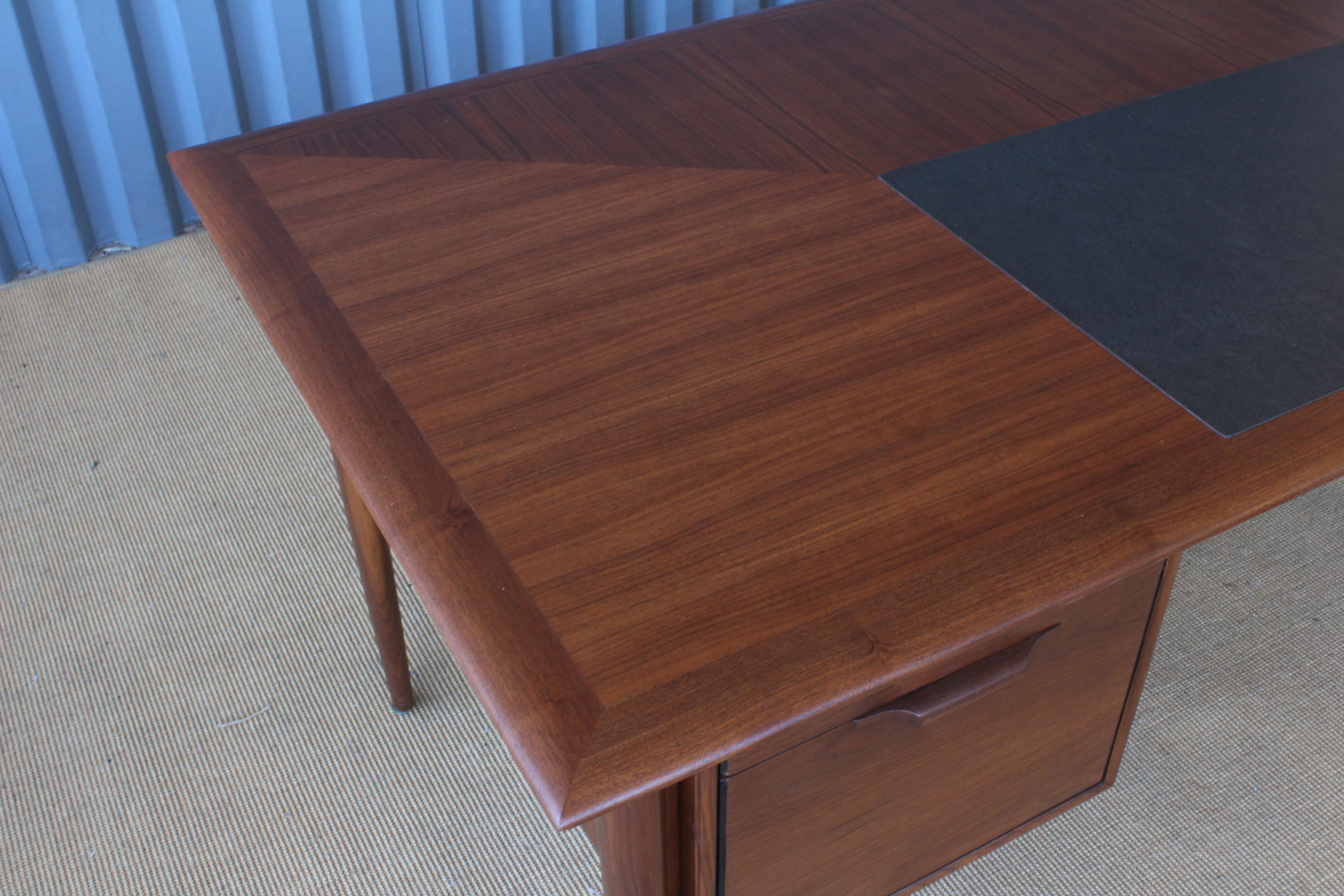 Large Danish style Mid-Century Modern executive desk in walnut. Recently refinished. Drawers all have sculpted walnut handles. Adjustable metal caps on the bottom of each leg.