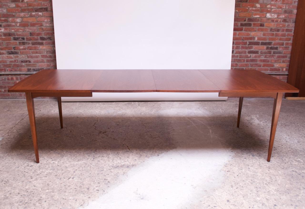 1950s walnut dining table supported by elegant, tapered legs designed by Kipp Stewart for Drexel’s “Declaration” line. Includes the two additional leaves. Beautifully bookmatched walnut veneer with only the most minor of tone differentiation between