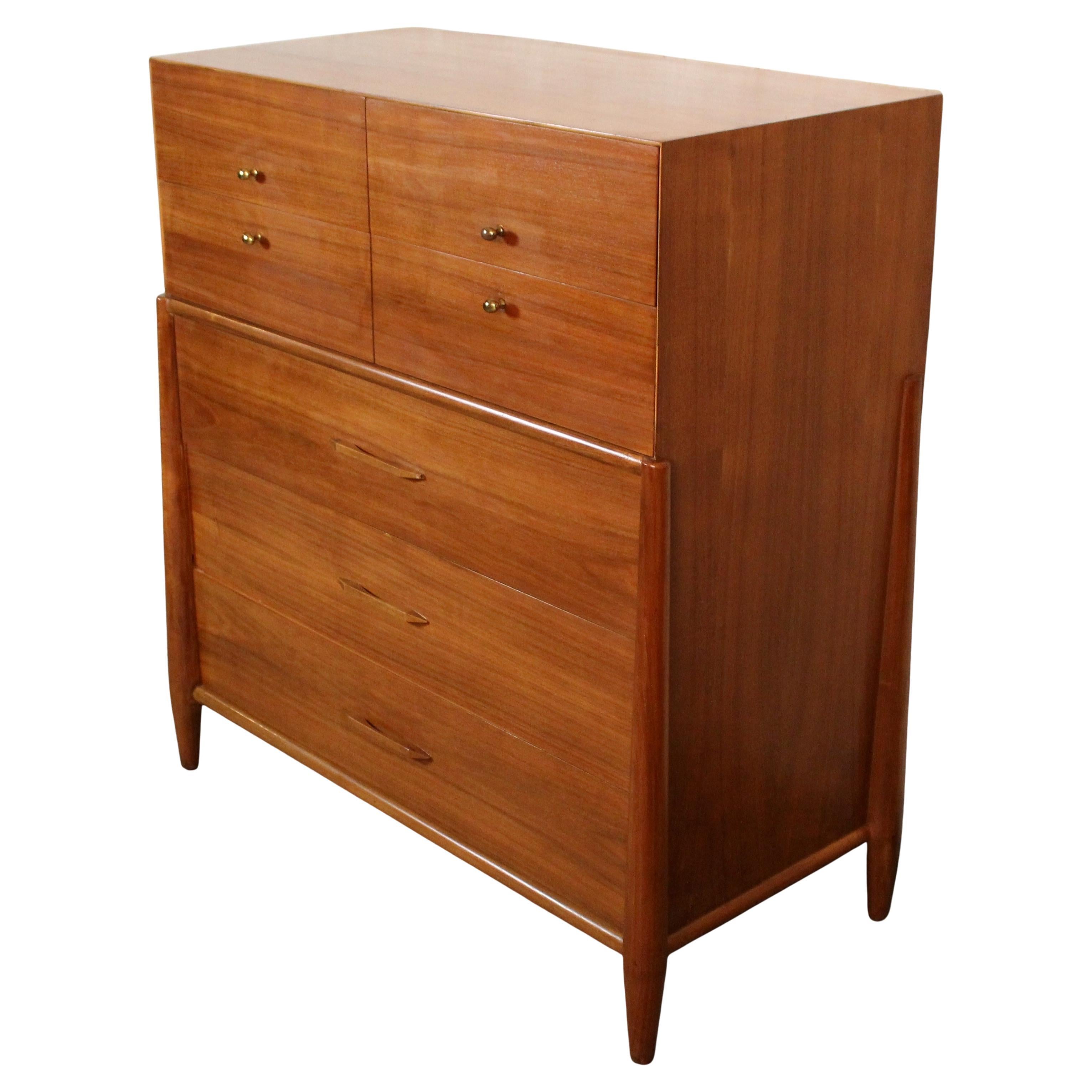 A striking example of mid‑century American craftsmanship, this highboy dresser by Modernage Furniture Co. is constructed in richly hued solid walnut with matching drawer fronts that showcase beautiful grain variation. Comprising five spacious